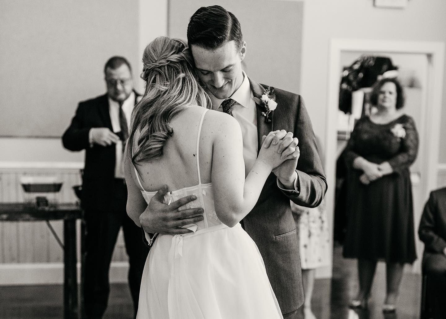 Bride and groom sharing their first dance in a tender embrace at a classic indoor wedding reception.