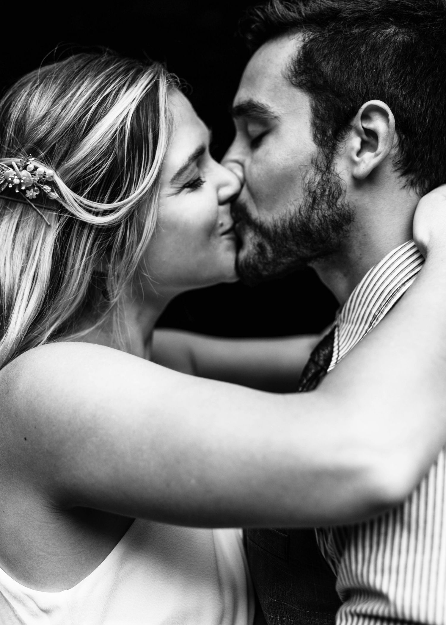 Black and white photo of bride and groom sharing a romantic kiss at their wedding.