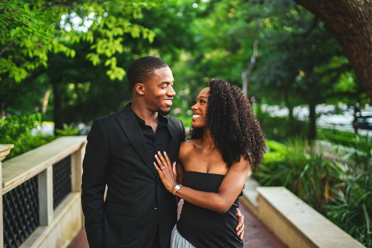 Happy Black couple sharing a tender moment on a garden bridge path.