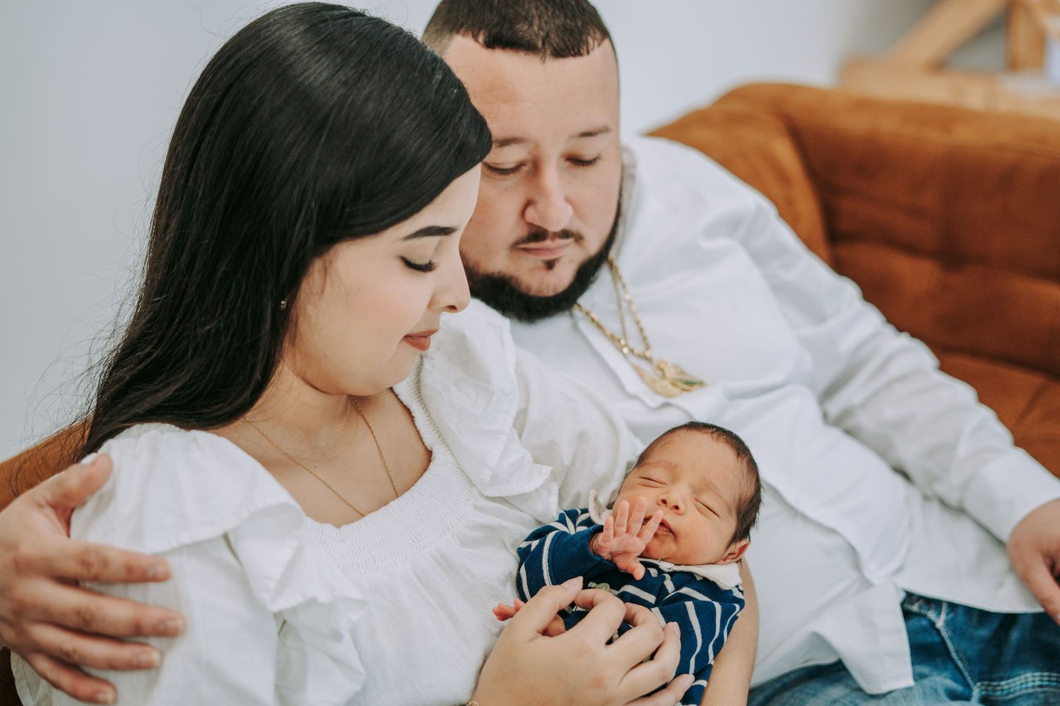 Loving couple admiring their newborn baby in a warm indoor setting.