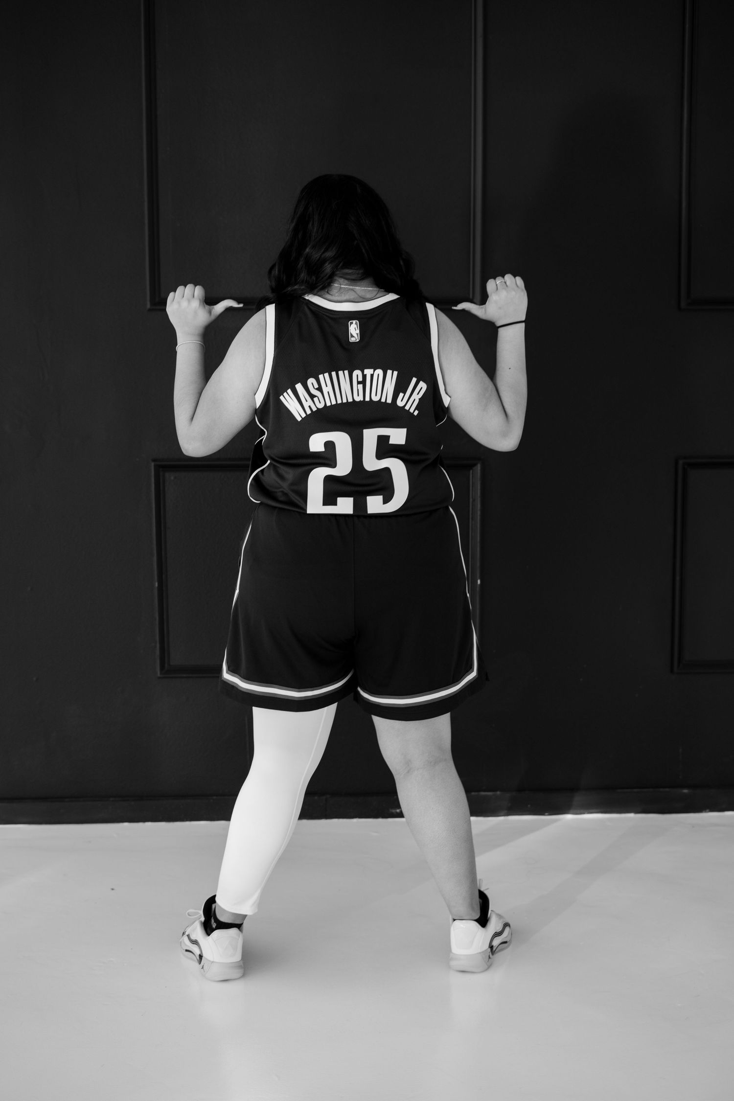 Black and white rear view of woman in Washington Jr. number 25 NBA jersey.