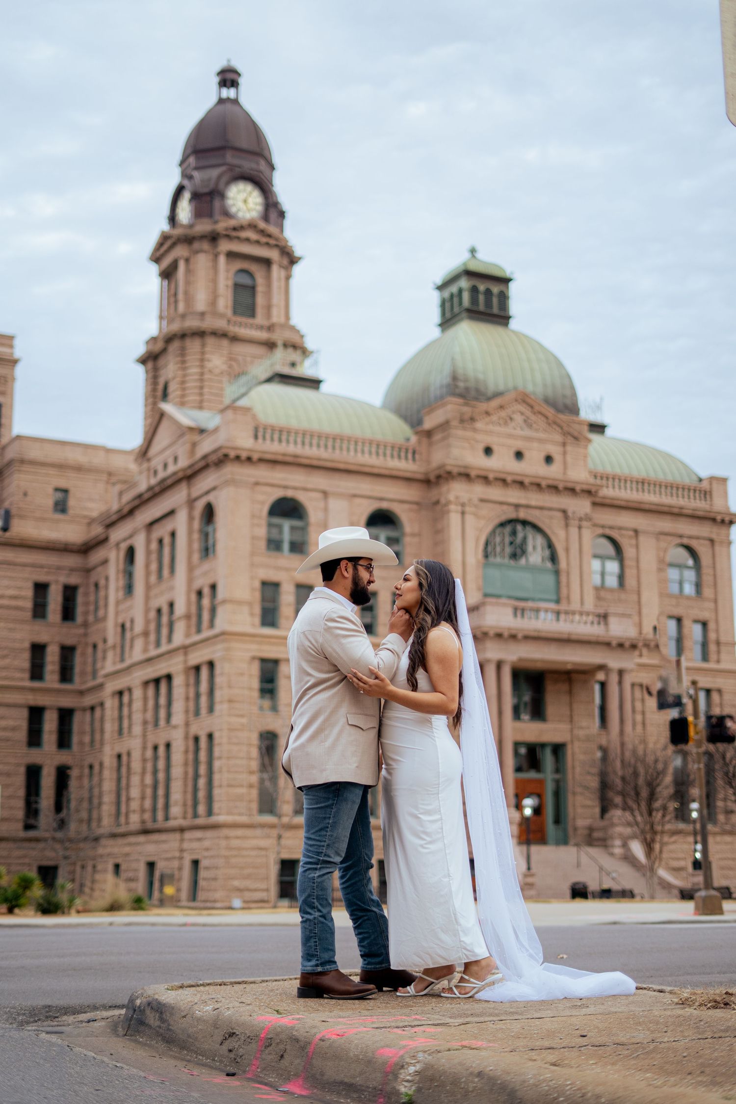 Bride and groom share a romantic moment in front of a historic domed Texas courthouse building.