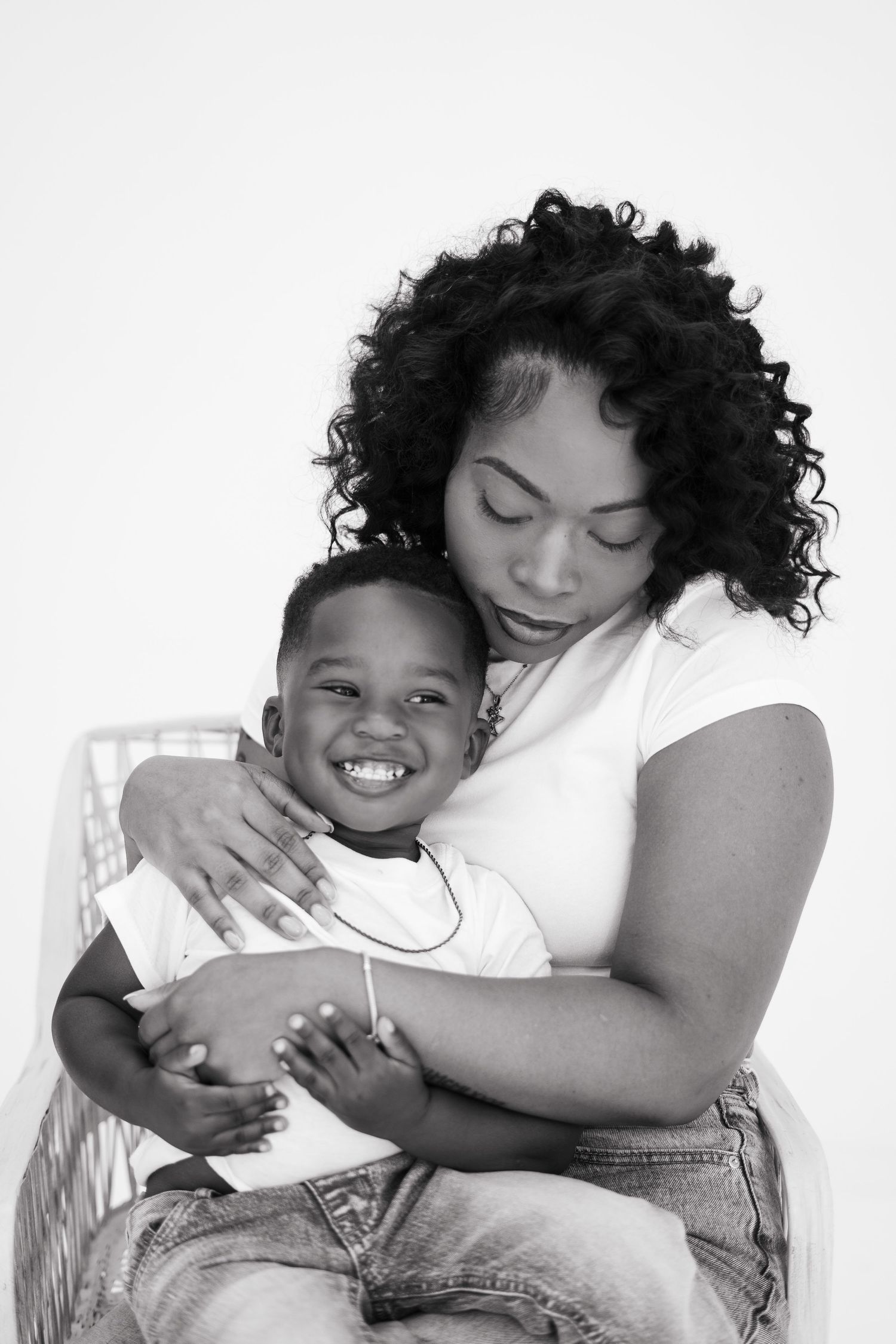 Black and white portrait of a mother tenderly embracing her smiling young son in studio.