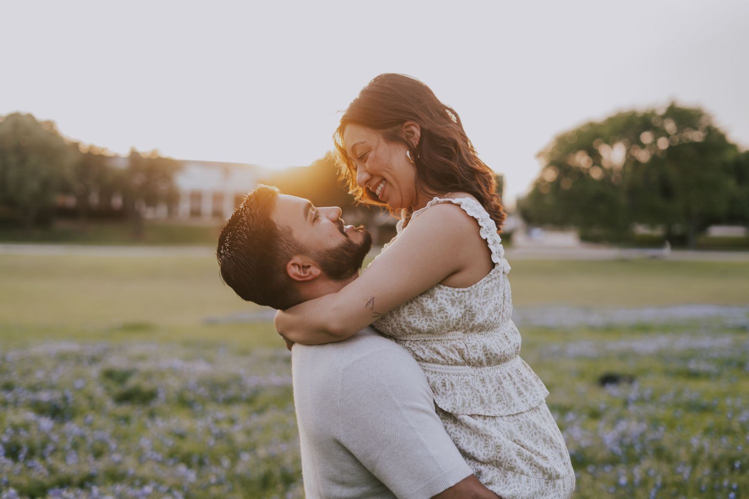 Couple embracing in a sunlit field of bluebonnets, sharing a joyful moment at golden hour.