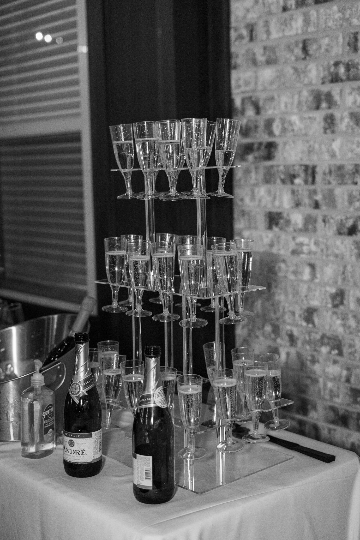 Black and white photo of champagne tower with glasses and bottles at an elegant wedding reception.