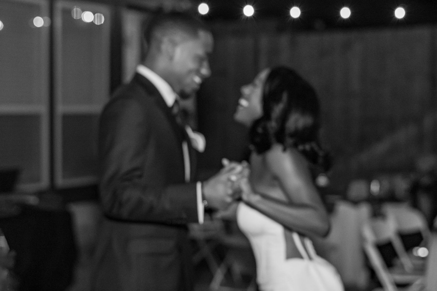 Black and white photo of bride and groom sharing first dance at wedding reception.