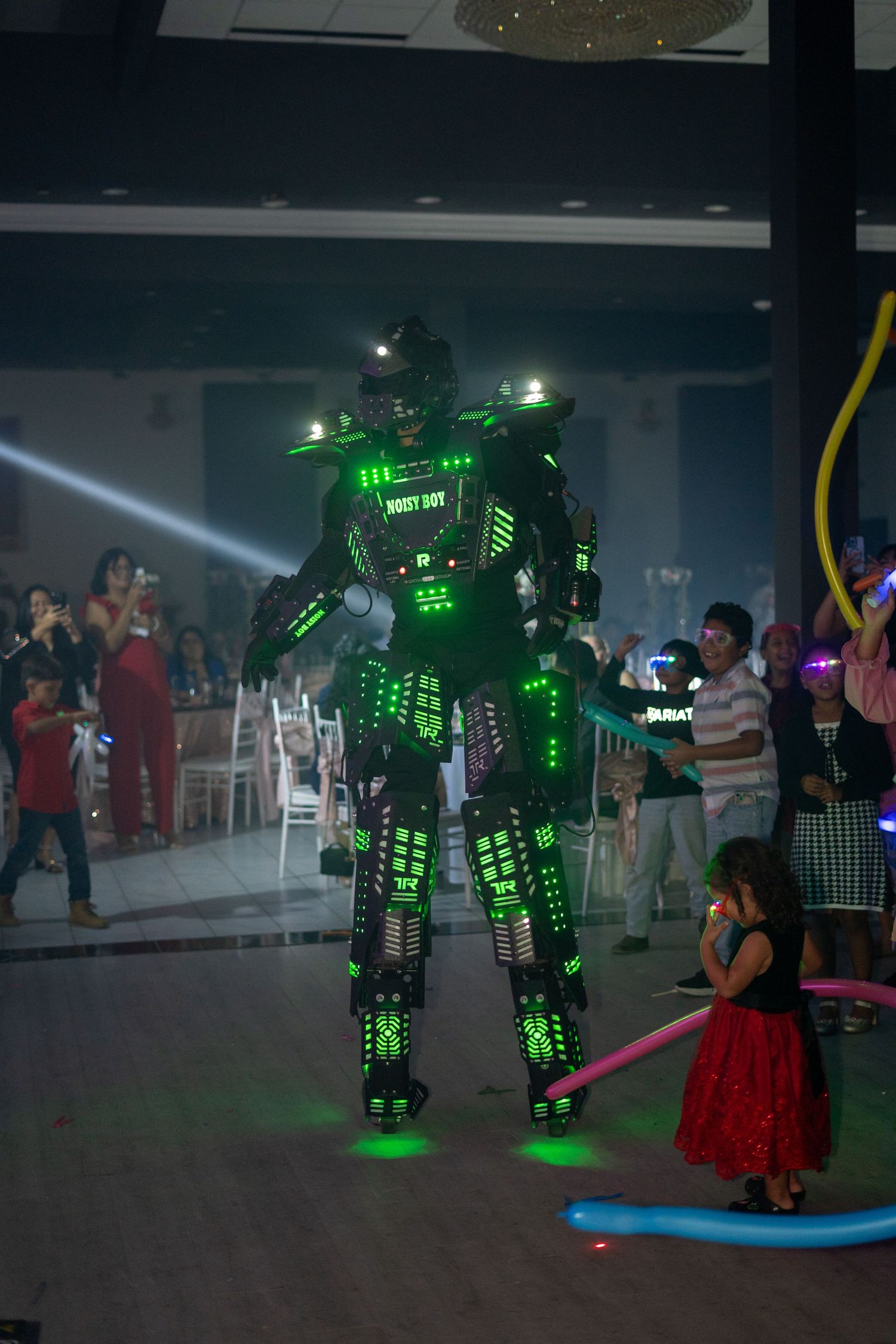 LED light-up robot performer entertains guests on dance floor at quinceañera celebration.