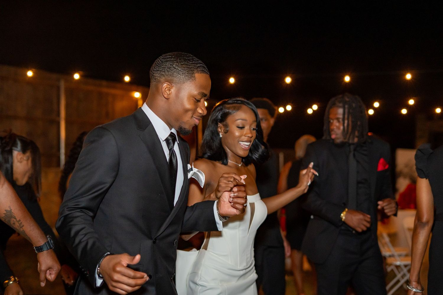 Newlywed couple sharing a dance together at their outdoor evening wedding reception celebration.