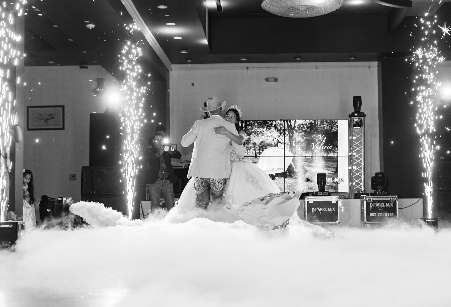 Black and white photo of quinceañera first dance surrounded by dramatic fog and sparkling fireworks.