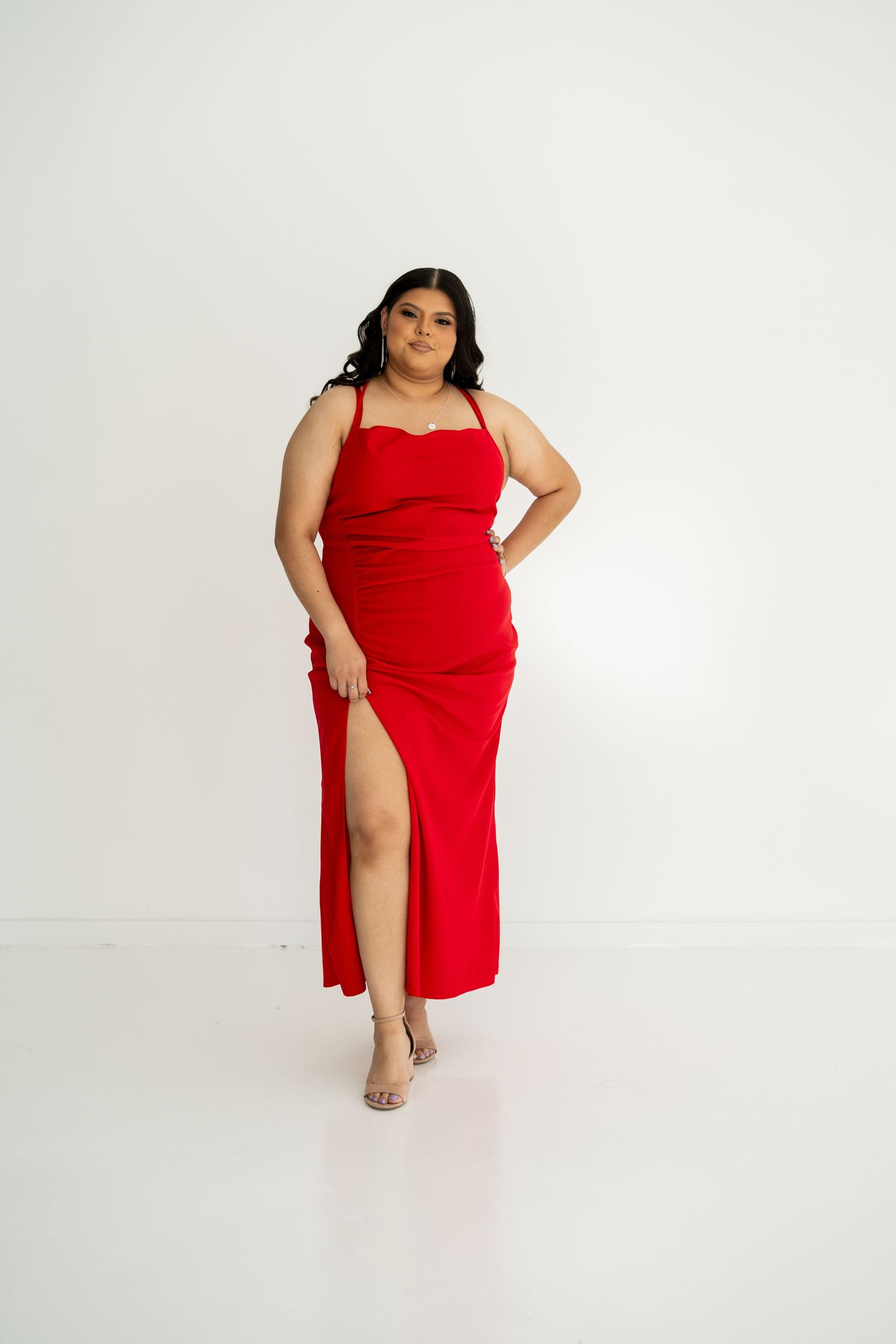 A woman in a red slit maxi dress poses gracefully against a clean white background.
