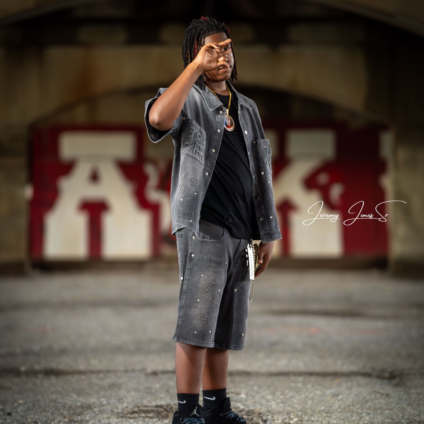 Child in gray jacket poses confidently in urban setting.