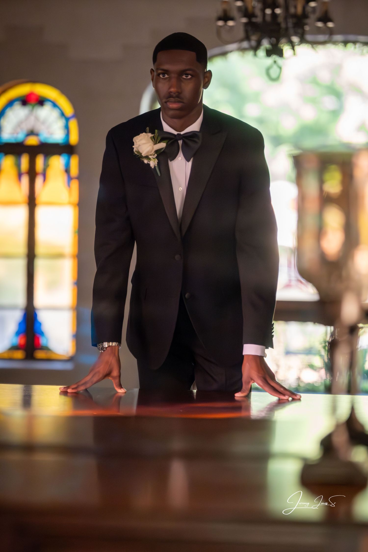 Formal portrait in church with stained glass windows in background.