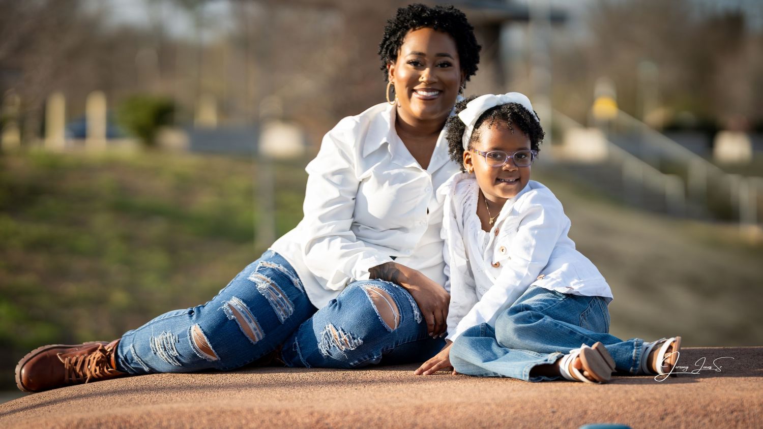 Family photoshoot outdoors with blurred natural background.