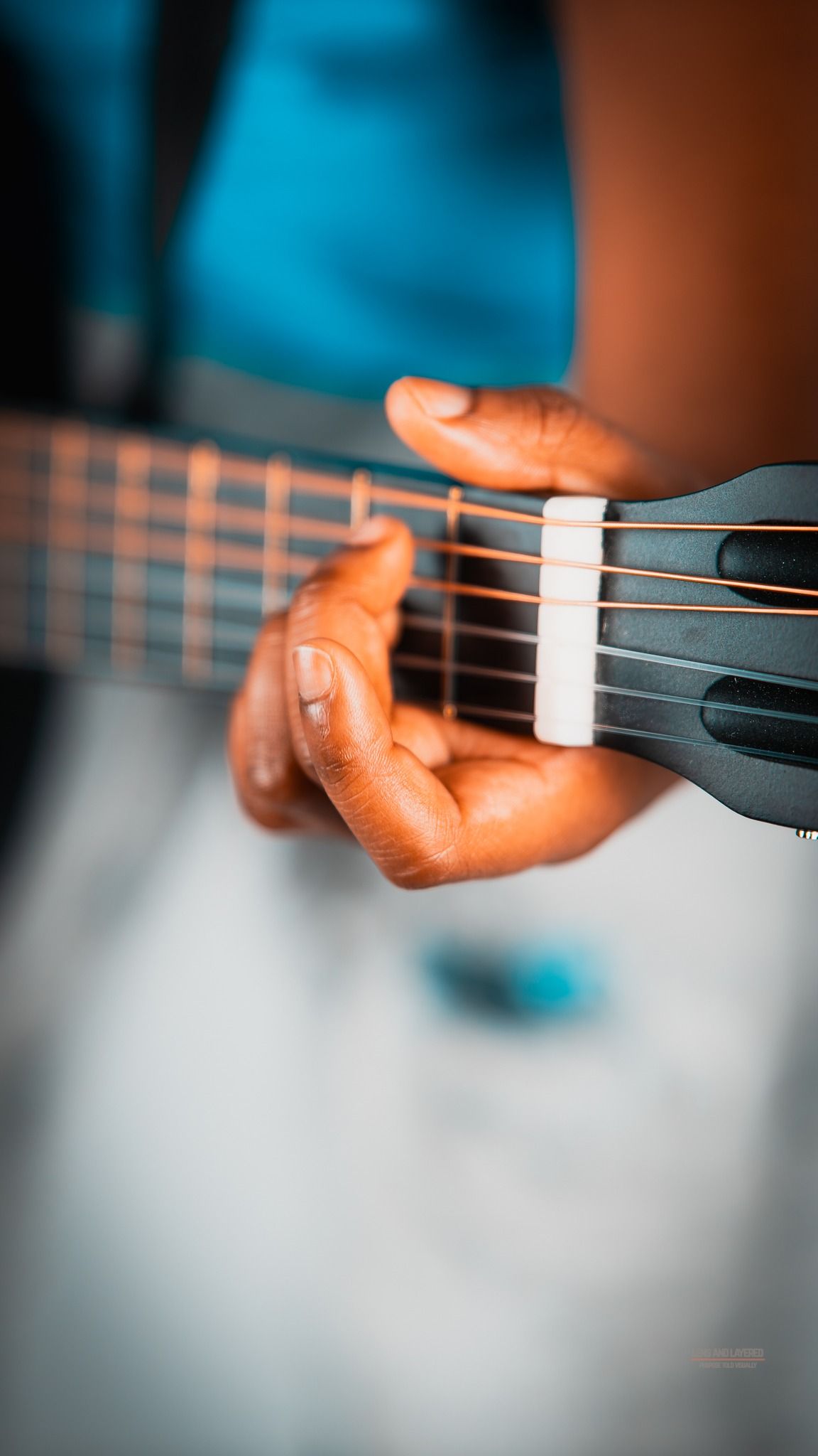 Close-up shots of hands playing a black acoustic guitar.