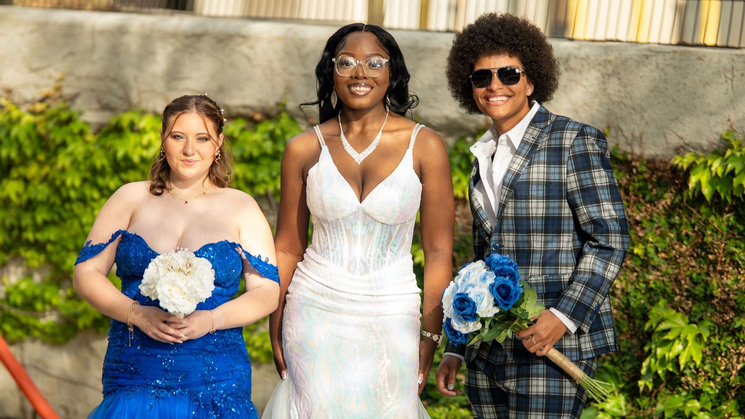 Prom group photo with blue and white attire standing together outdoors.