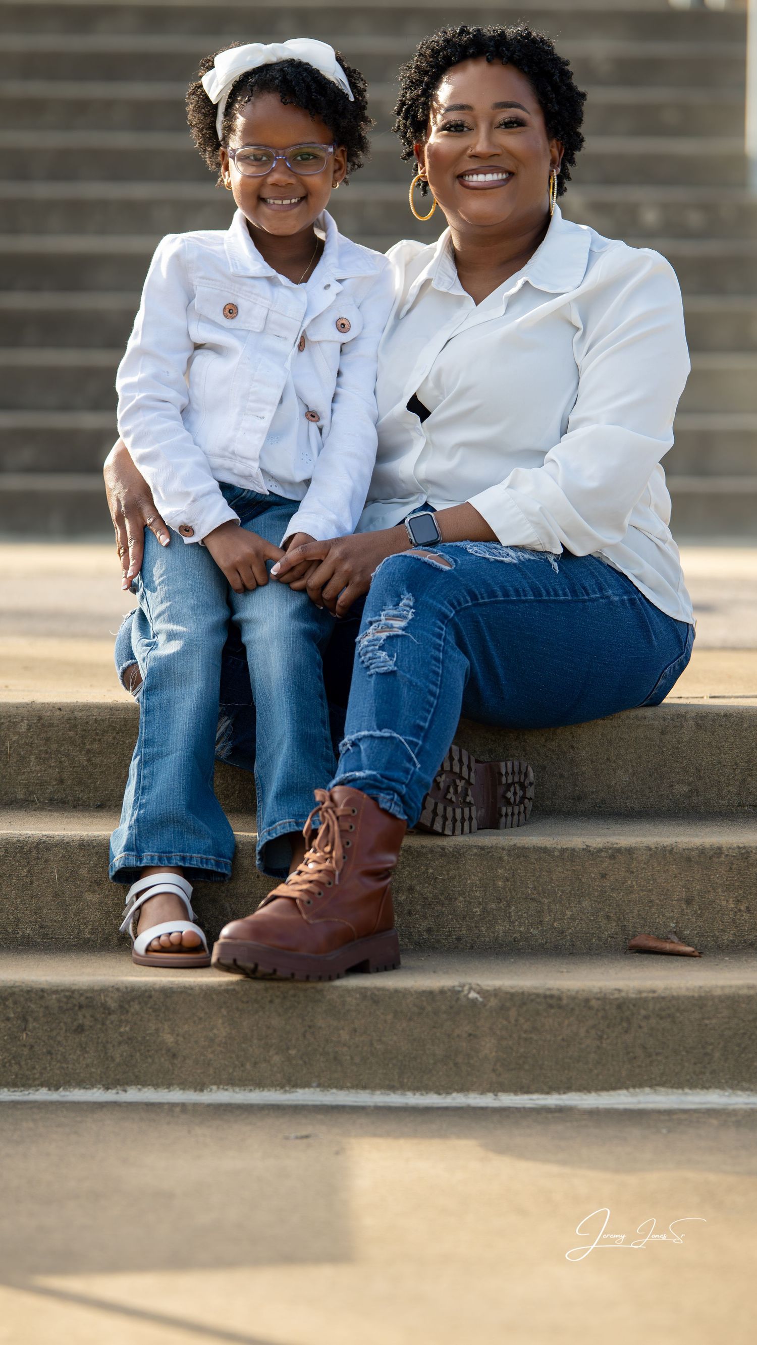 Relaxed outdoor portrait on steps featuring coordinated white tops and jeans.