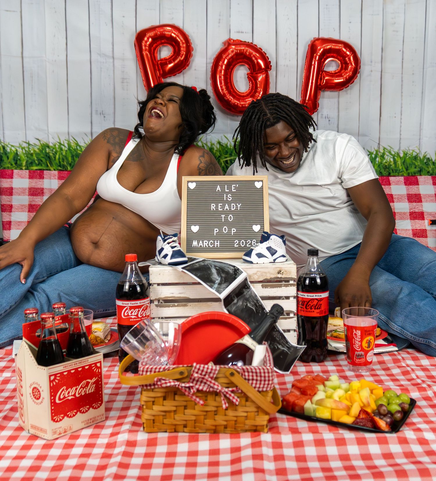 Picnic setup with Coca-Cola, snacks and red checkered tablecloth featuring festive pop balloons.