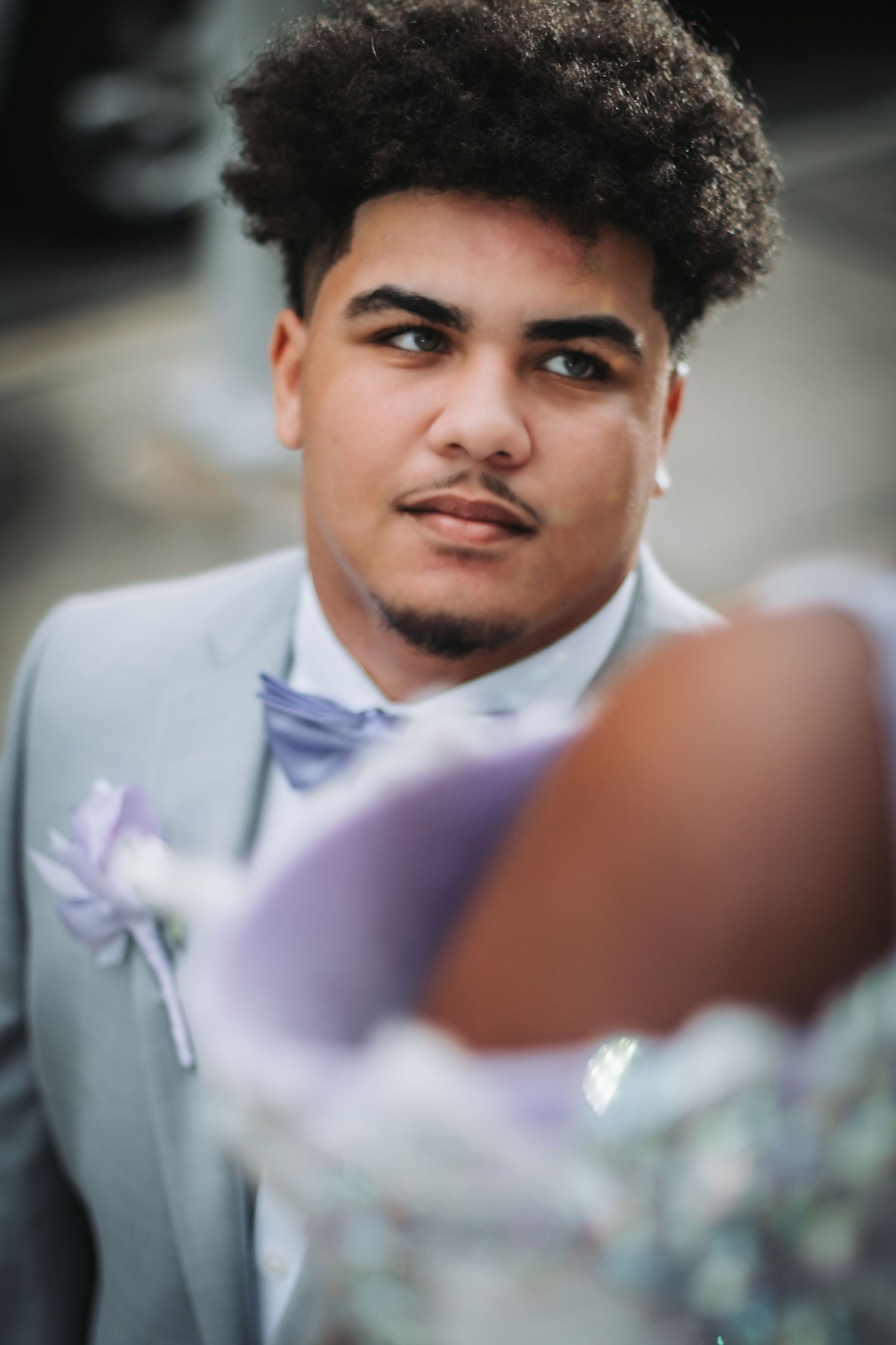 Groom in light gray suit with lavender bow tie at wedding ceremony.