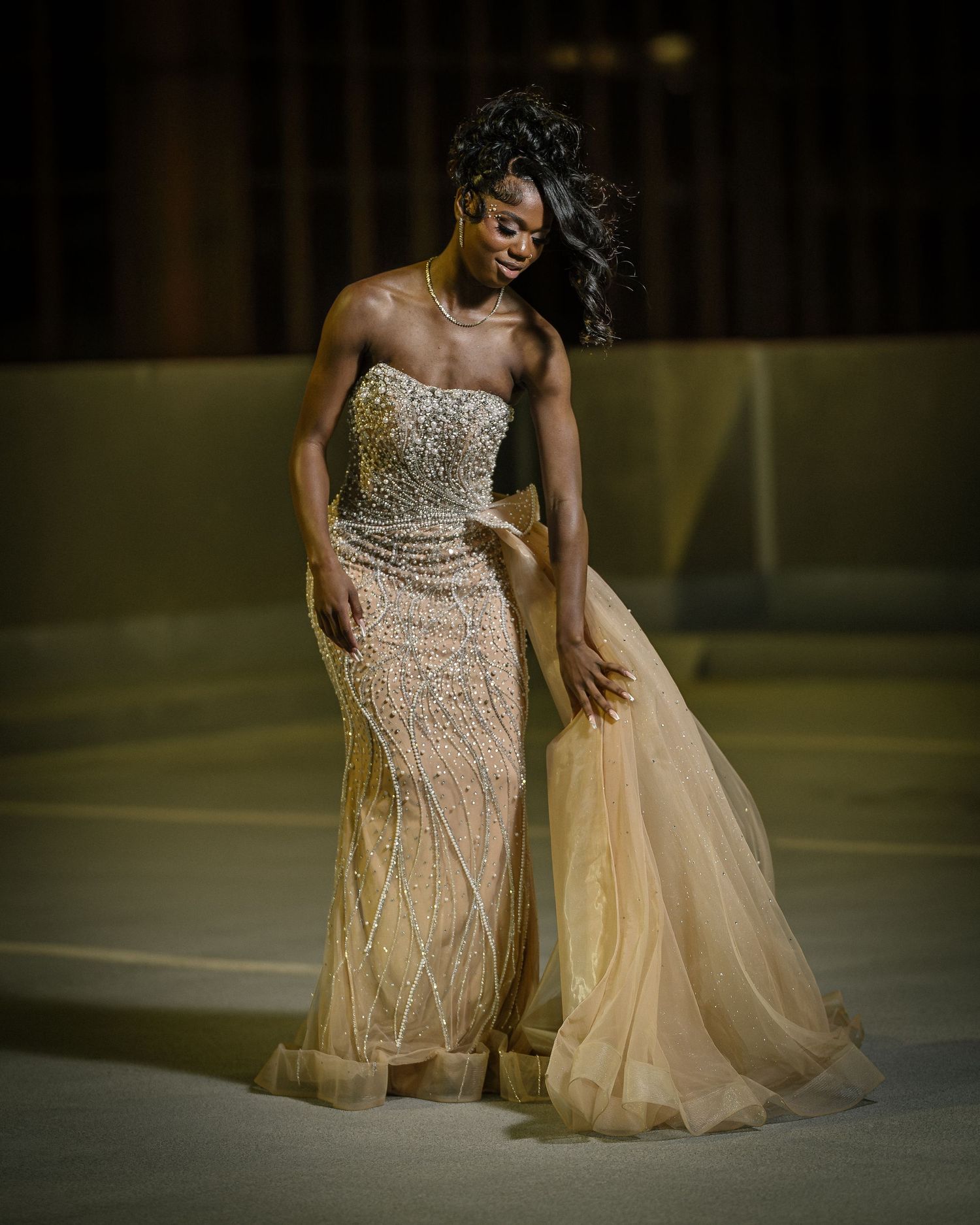Elegant evening gown in champagne beige with intricate beading and flowing tulle overlay creates a stunning silhouette.