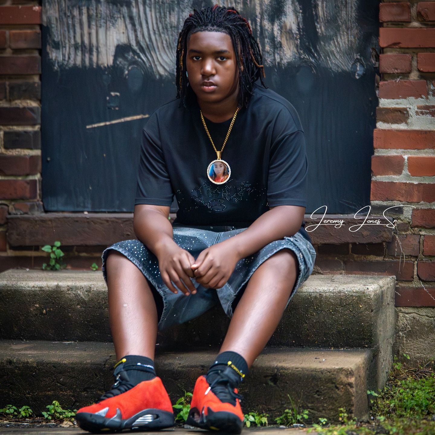 Person wearing black clothing and red sneakers sits on brick steps in an artistic portrait series.