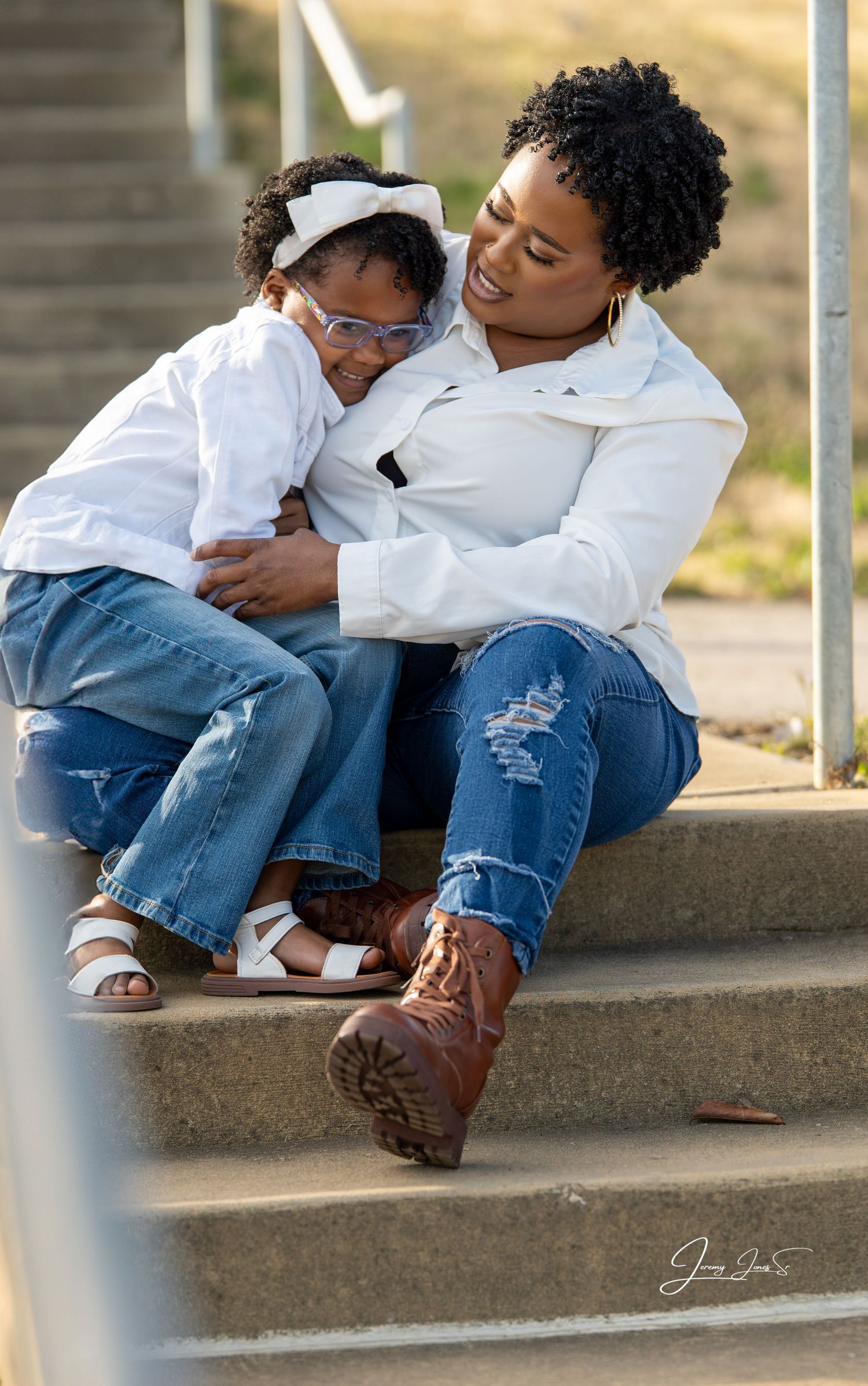 Casual portrait on concrete steps showing matching white tops and denim.