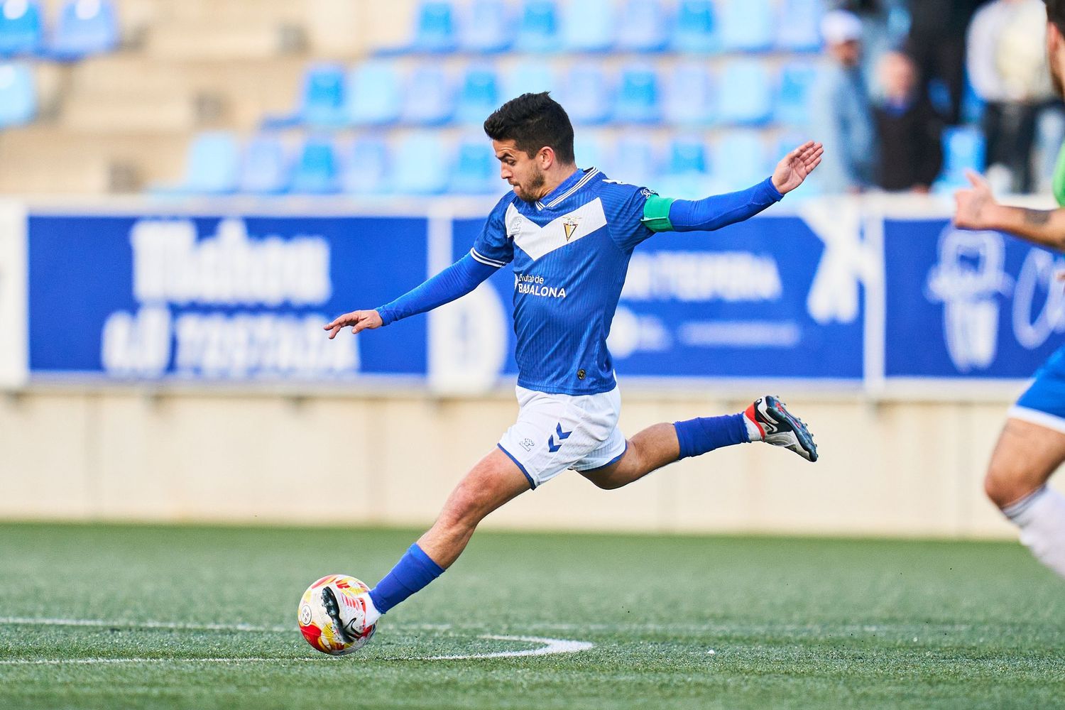 Fotografia esportiva de futbol juvenil a Barcelona amb jugador xutant des de la banda