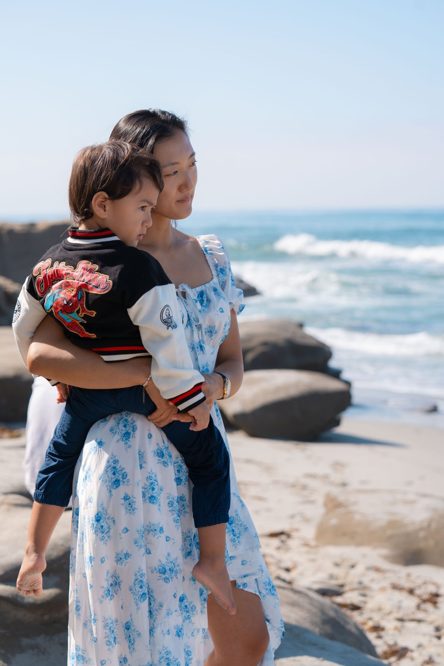 Mother holding toddler on coastal rocks during a natural outdoor family photography session captured by a Colorado family photographer.