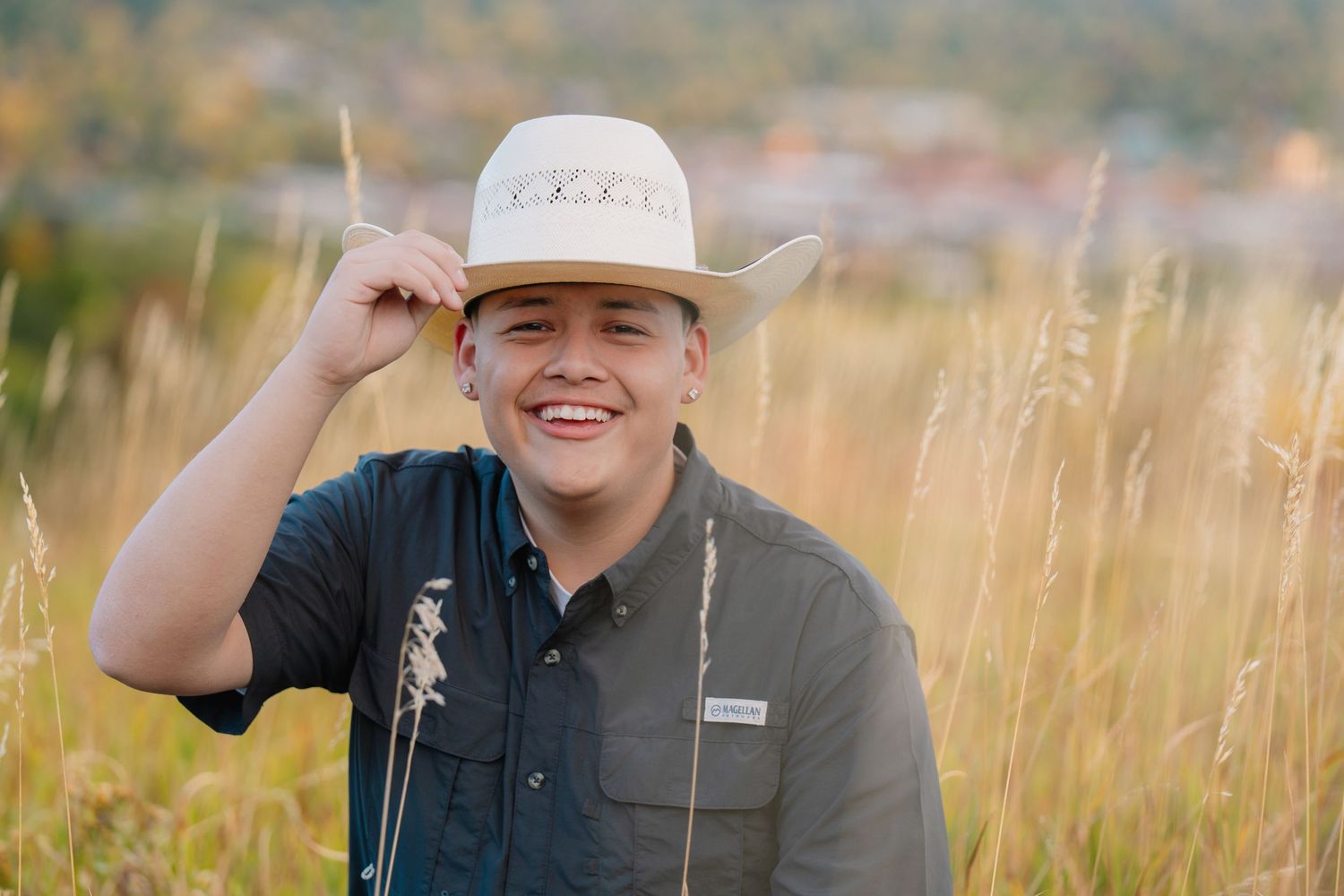 Senior portrait in golden field with cowboy hat during an outdoor senior photography session captured by a Colorado senior photographer.
