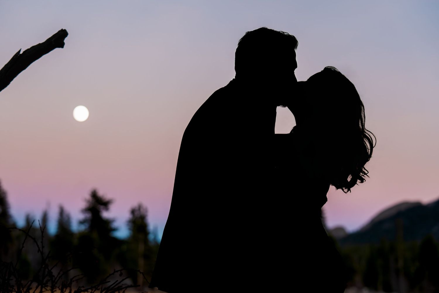 Silhouette of couple kissing at sunset during a romantic engagement photo session in Rocky Mountain National Park.