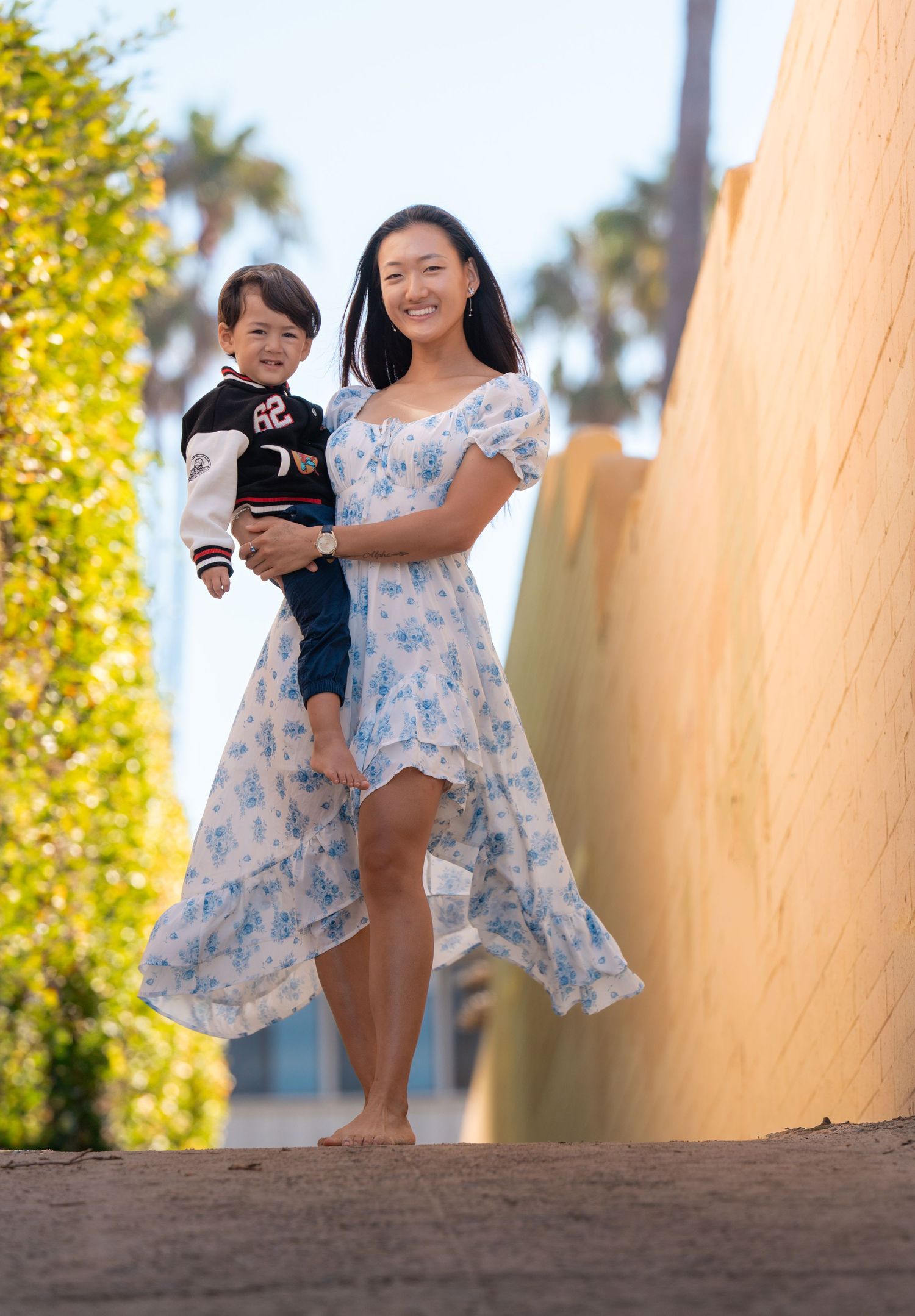 Mother holding her toddler while walking outdoors during a relaxed lifestyle family photography session photographed by a Denver area family
