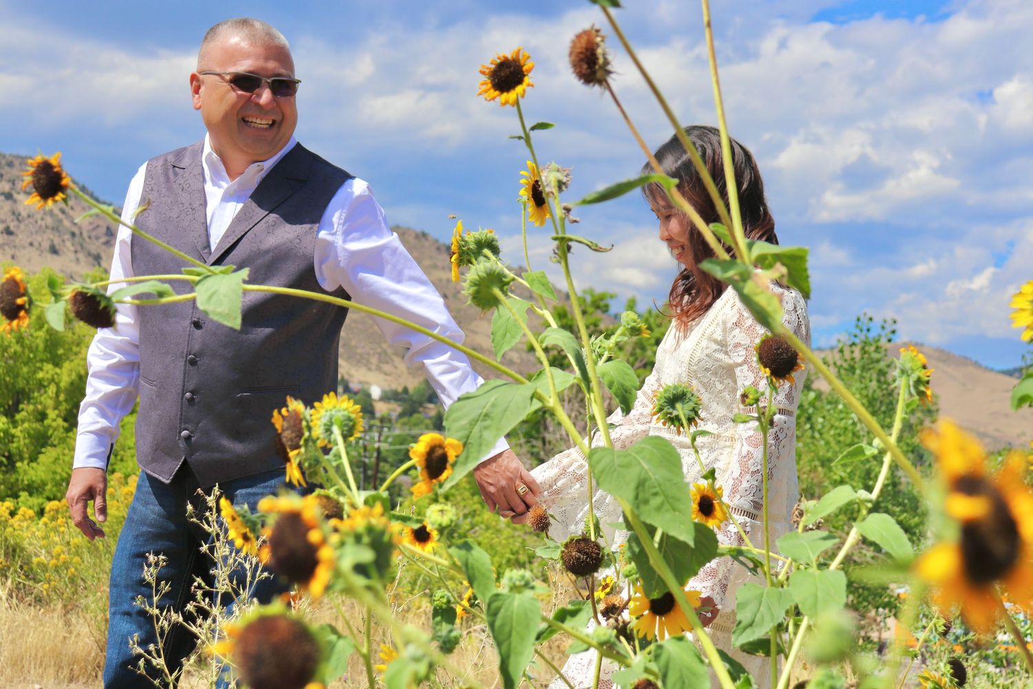 Couple walking through sunflower field during a joyful outdoor lifestyle photography session captured by a Colorado couples photographer.