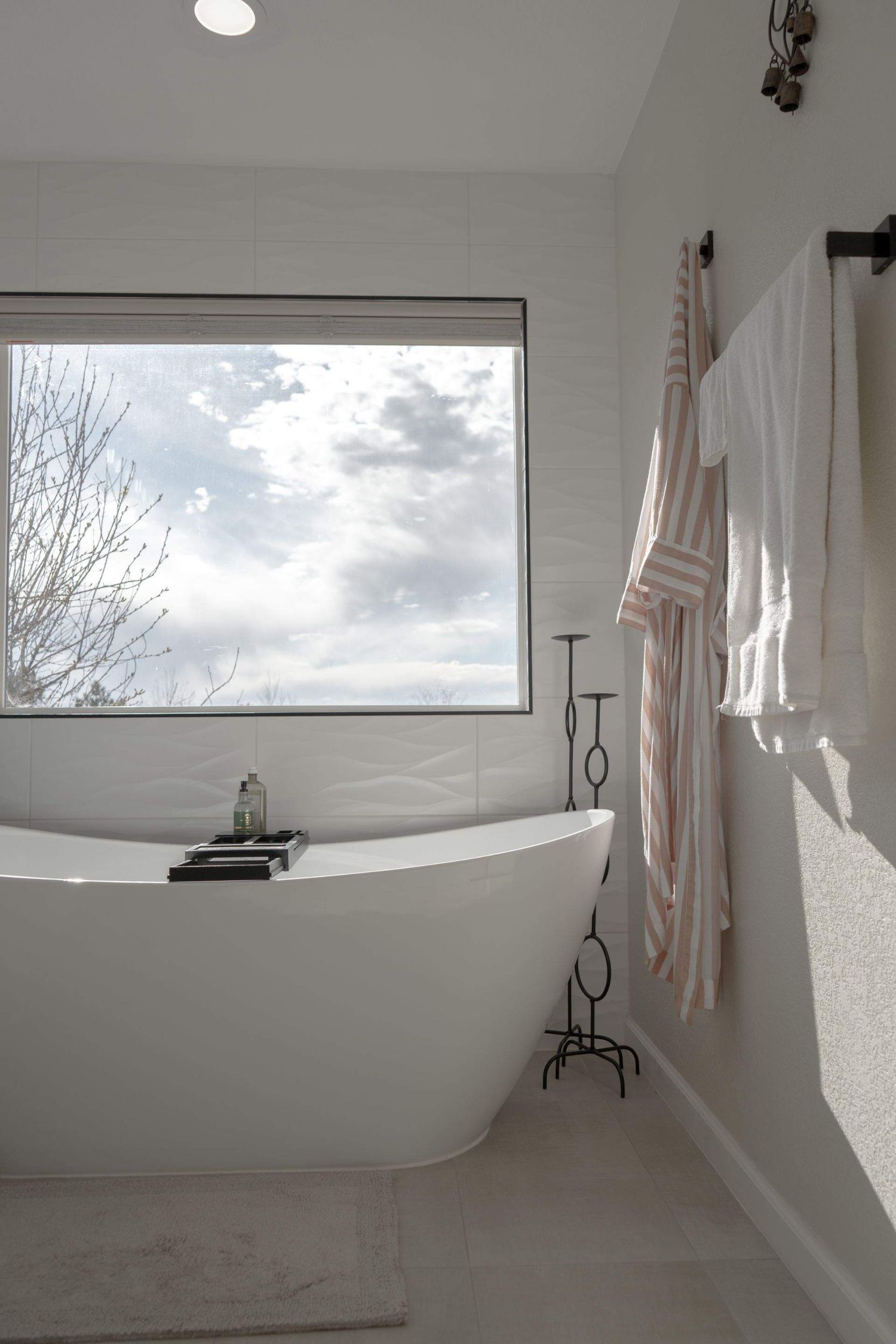 Bright bathroom with a freestanding soaking tub and a large window, captured for interior and real estate photography in Colorado.