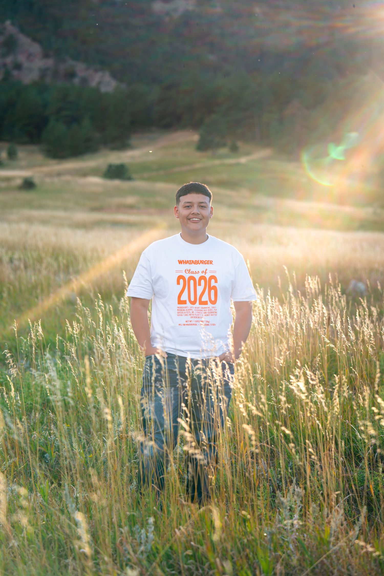 Prairie View High School senior leaning on a wooden fence with the Colorado mountains during an outdoor senior portrait session.