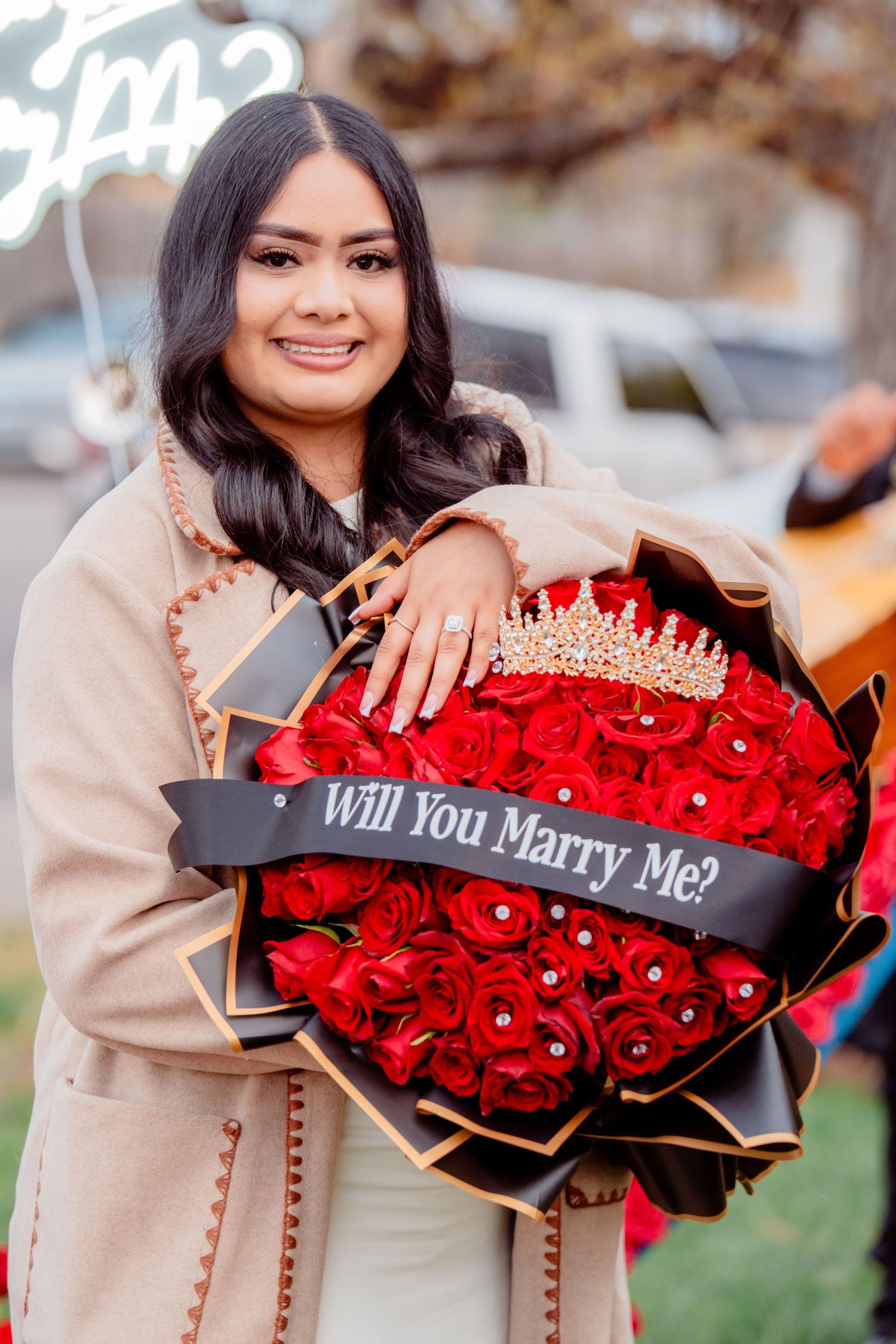 Portrait of woman holding red roses and engagement ring after a romantic proposal captured during a couples photography session.