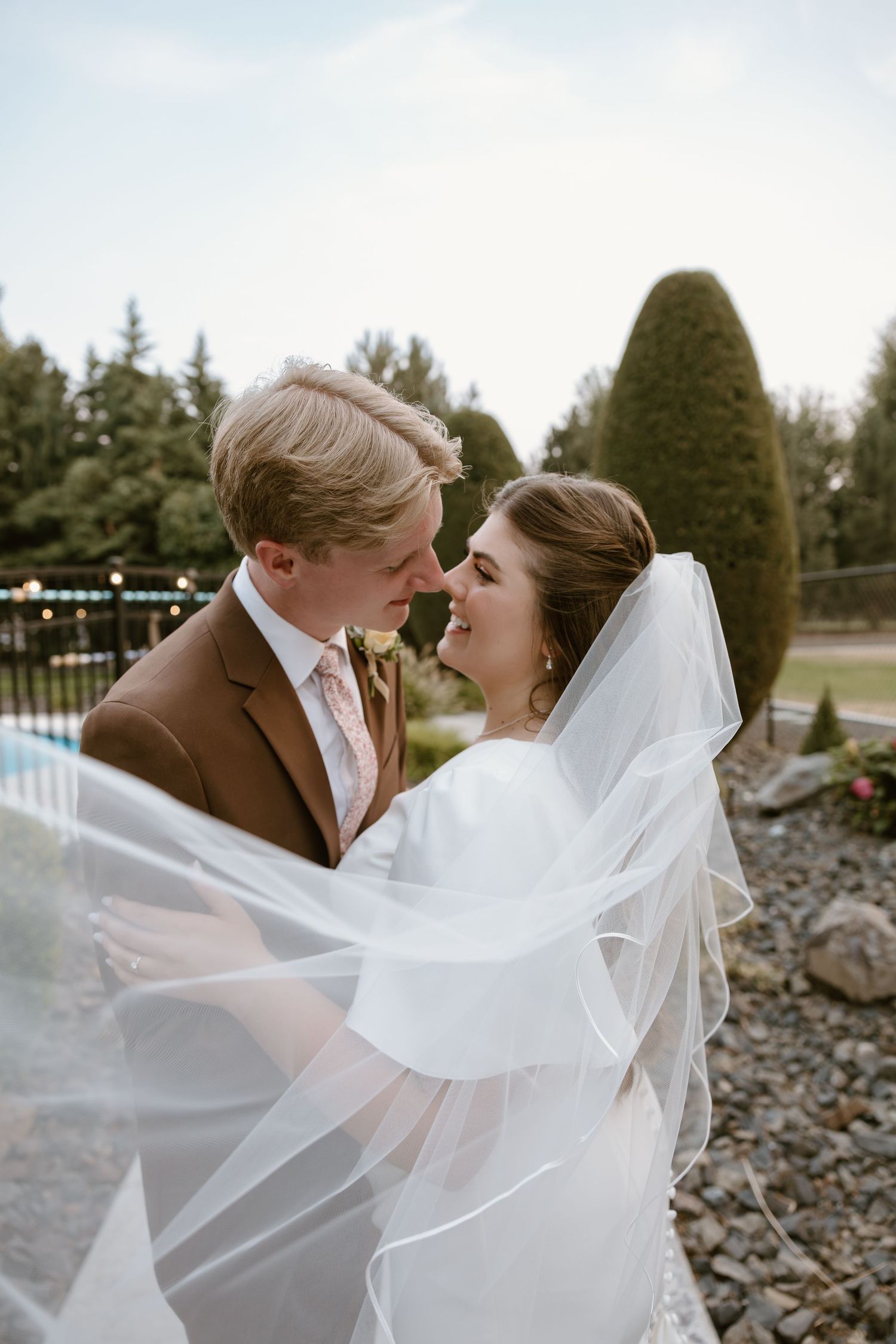 A romantic wedding couple embraces as the bride's veil flows gracefully in the wind across multiple candid moments.