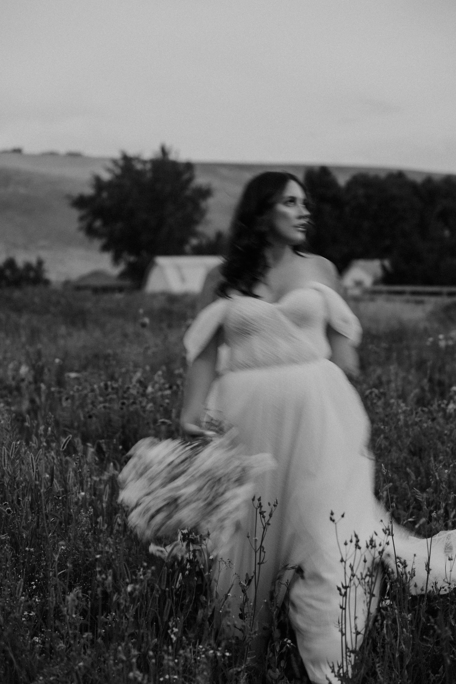 A black and white photo series shows a figure in white spinning through a wildflower field in an ethereal dance.