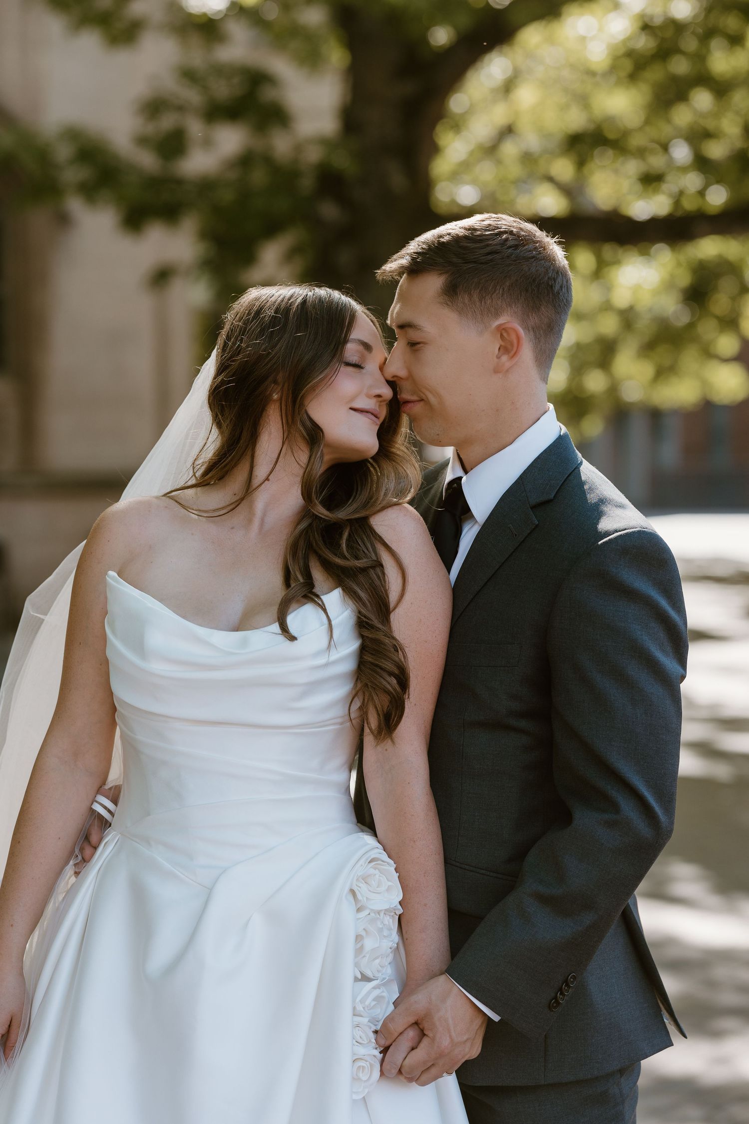 A romantic wedding couple embraces in a series of intimate outdoor portraits with soft natural lighting.