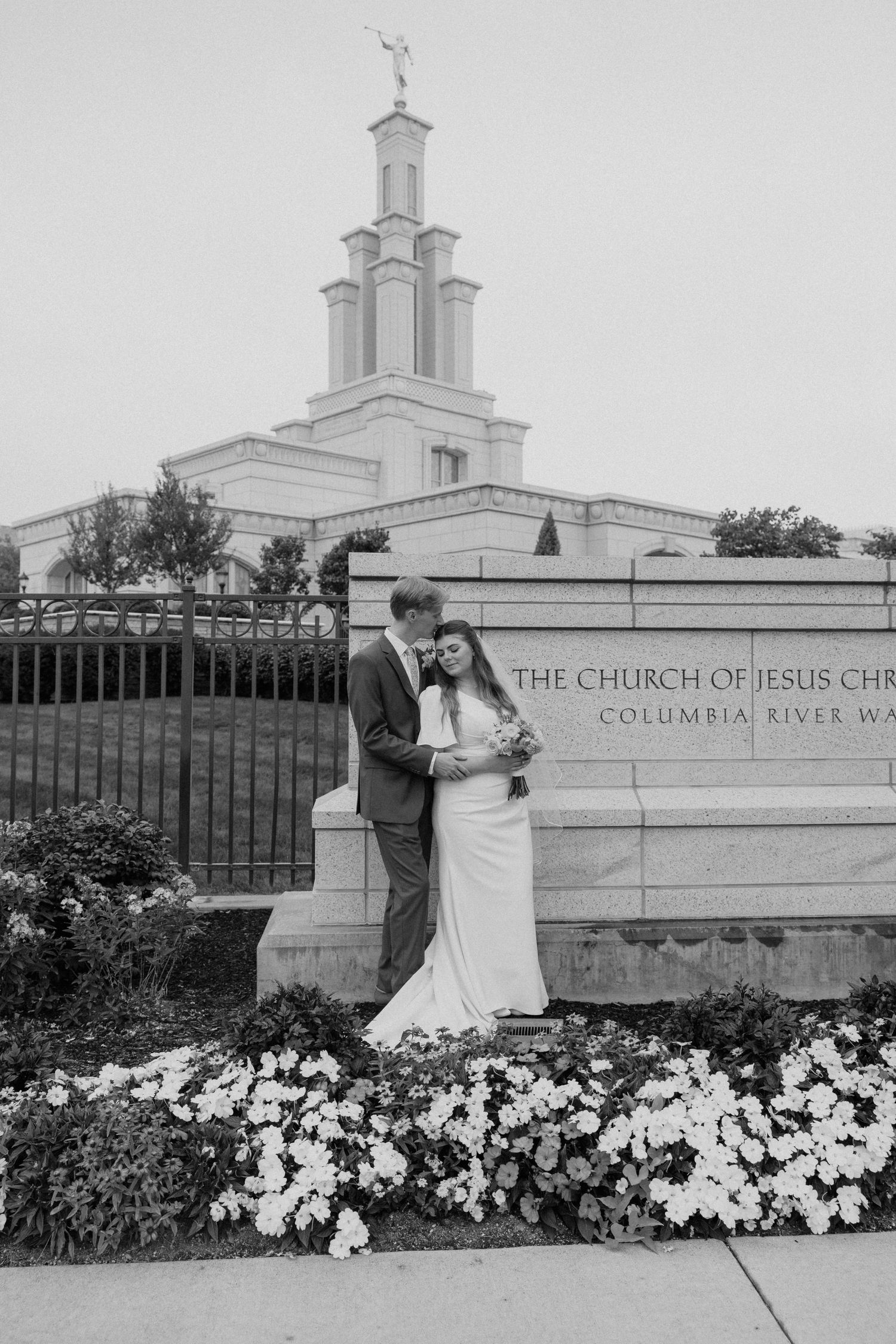 Black and white wedding photos in front of the Columbia River LDS Temple with white flowers in the foreground.