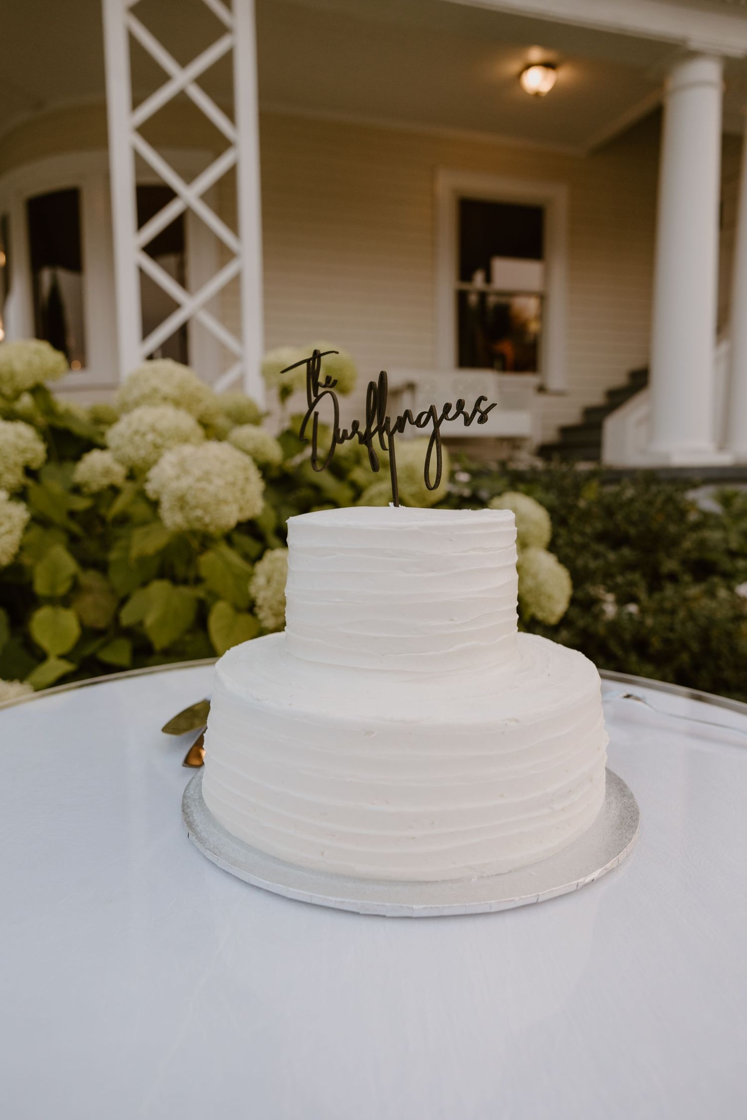 A series of white wedding cake tiers shown from different angles on a table with hydrangeas in the background.