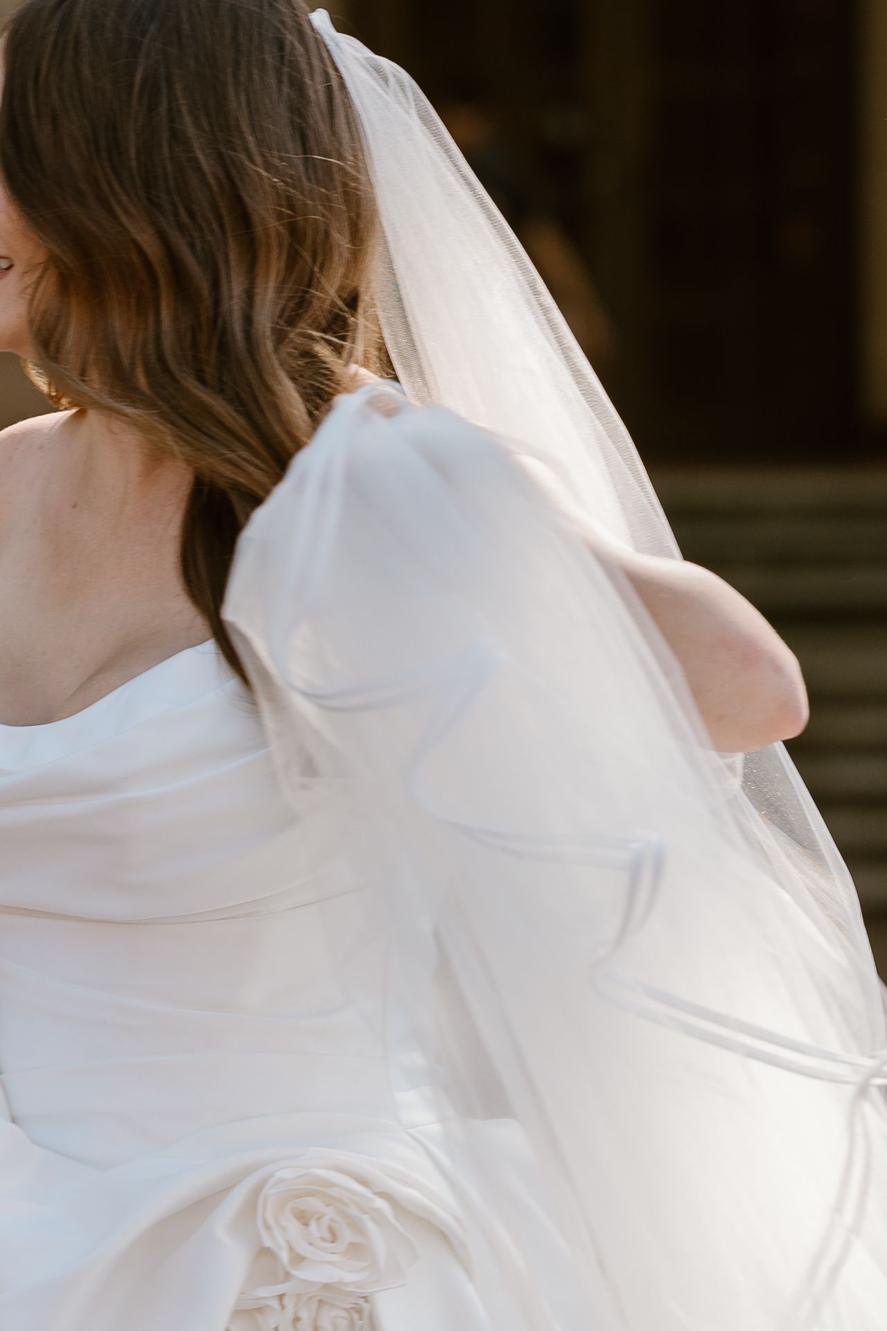 A flowing white bridal veil catches the light as it billows gracefully in the wind.