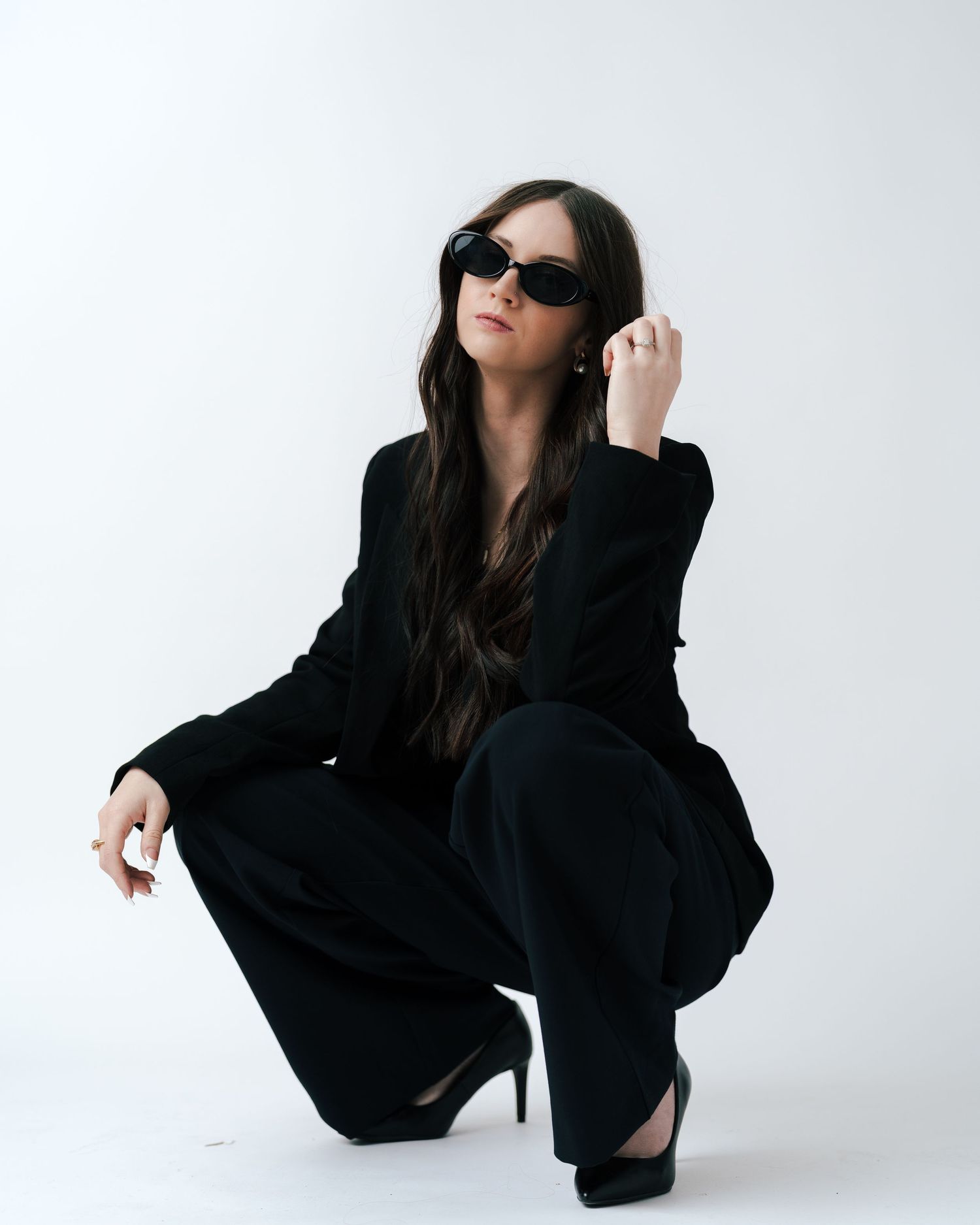 Fashion model in black outfit poses against white backdrop in artistic studio shots.