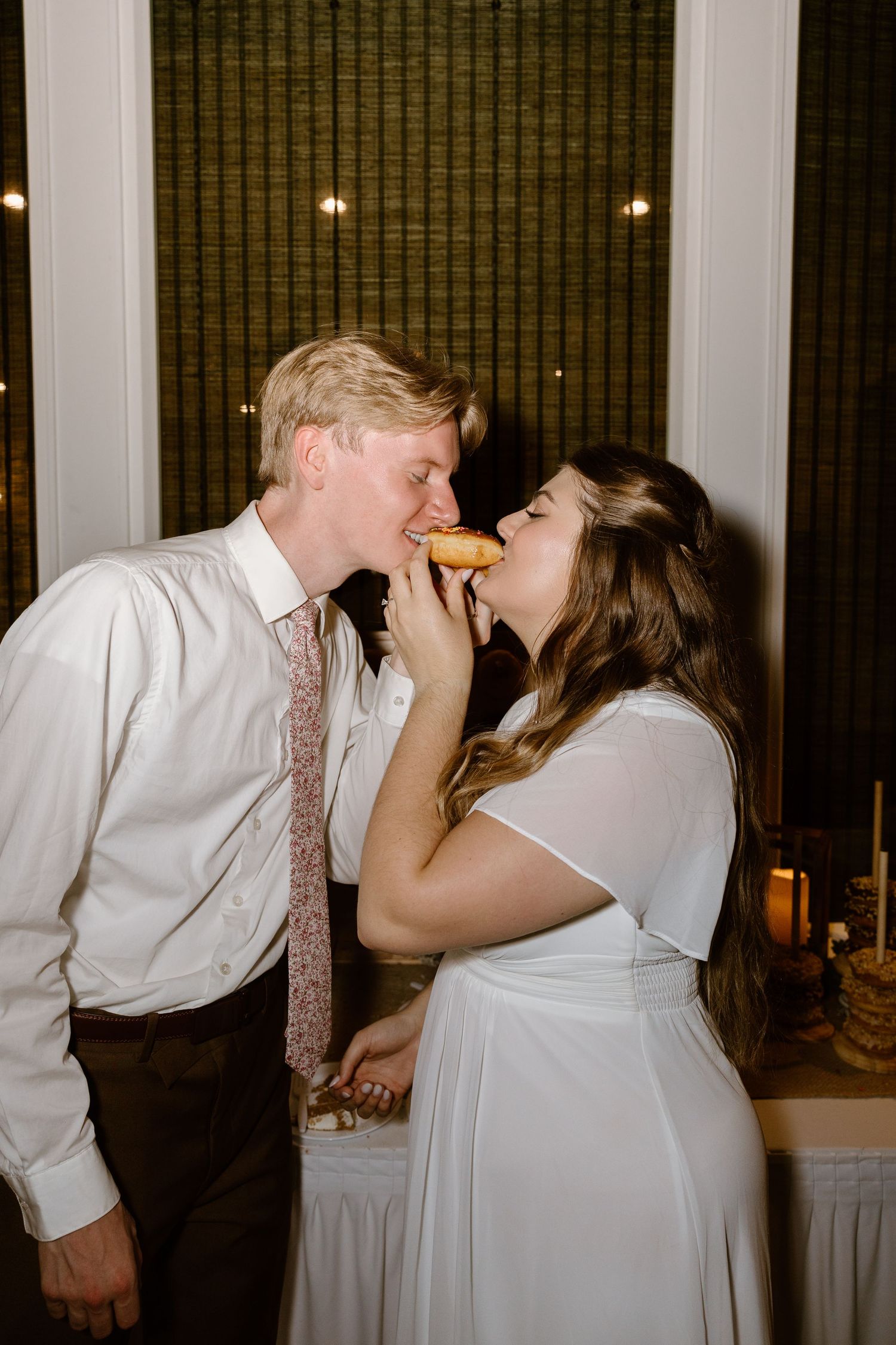 A couple shares a joyful cake-feeding moment during their wedding reception celebration.