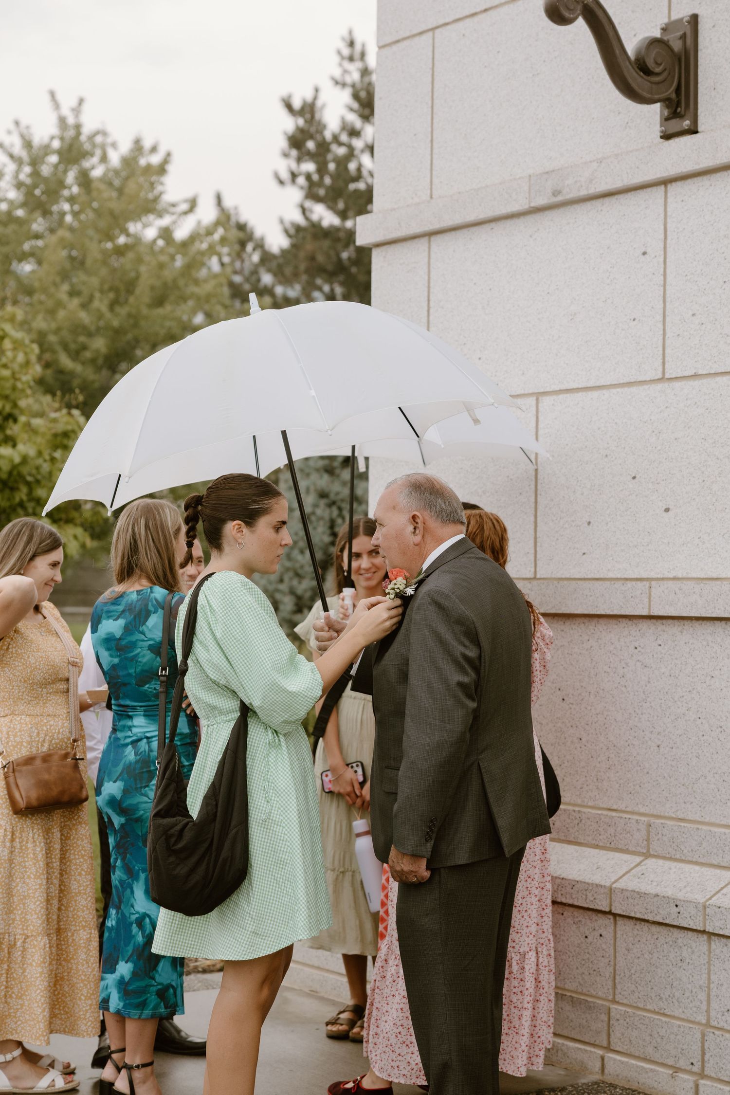 A sequence of photos showing guests with umbrellas greeting each other outside a white building on a rainy day.