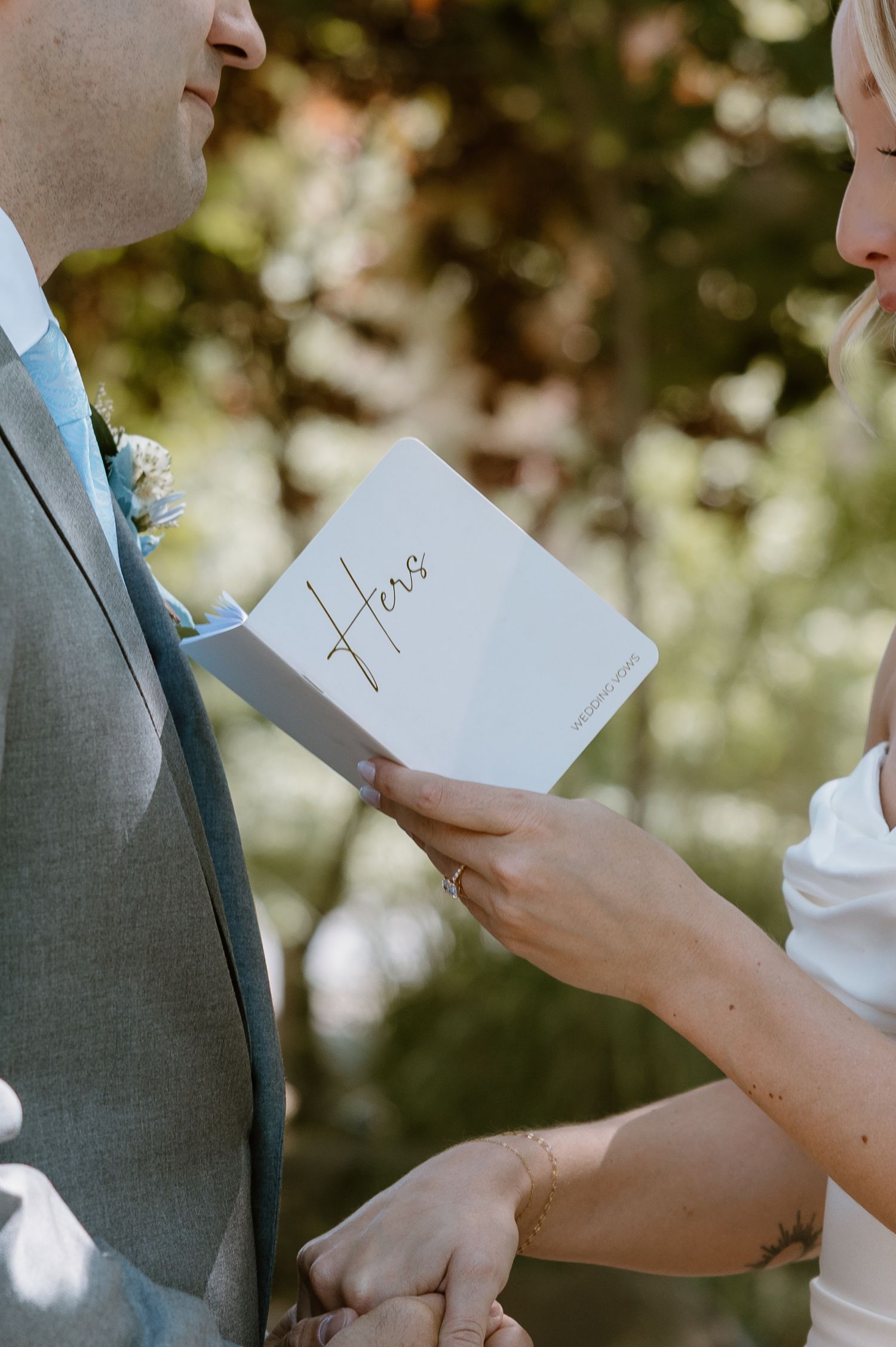 A couple exchanges handwritten vows during an intimate outdoor wedding ceremony in a garden setting.