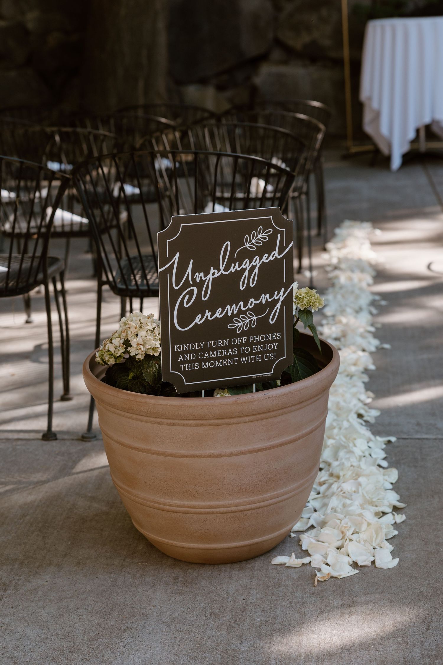 Decorative clay pots with elegant black ceremony signs and white flower petals scattered on the ground.