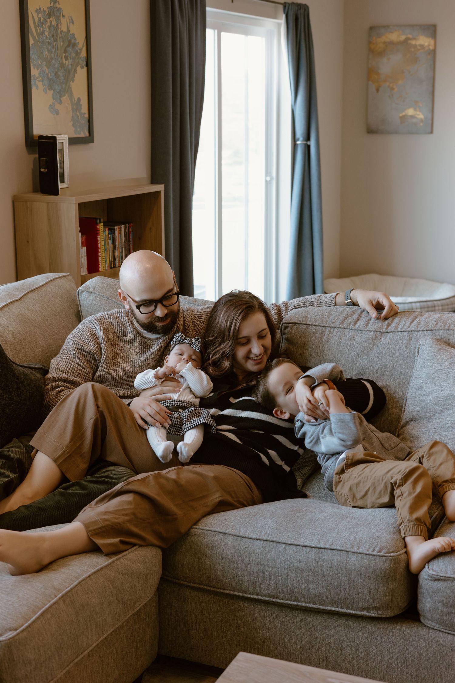 A cozy scene of relaxation on a gray couch with family members.