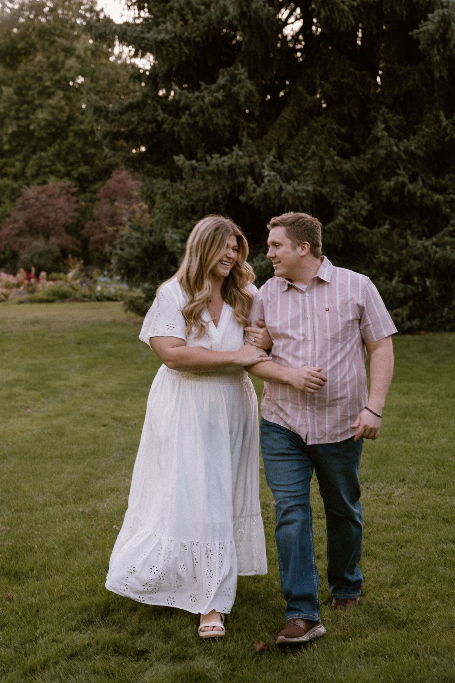 A couple shares tender moments together in a grassy outdoor setting during a romantic photo session.