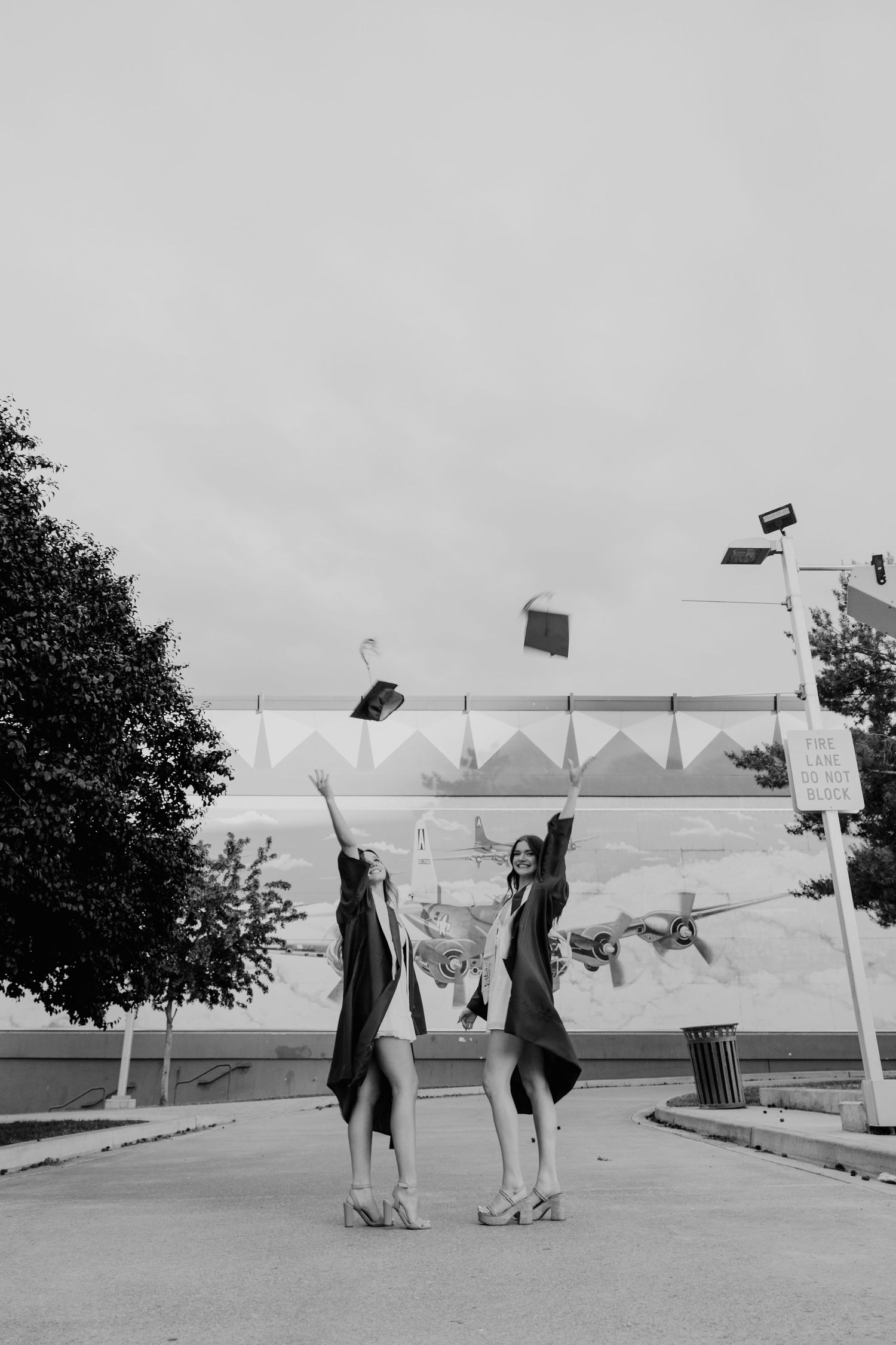 Senior high school graduates toss their caps in vintage black and white photography.