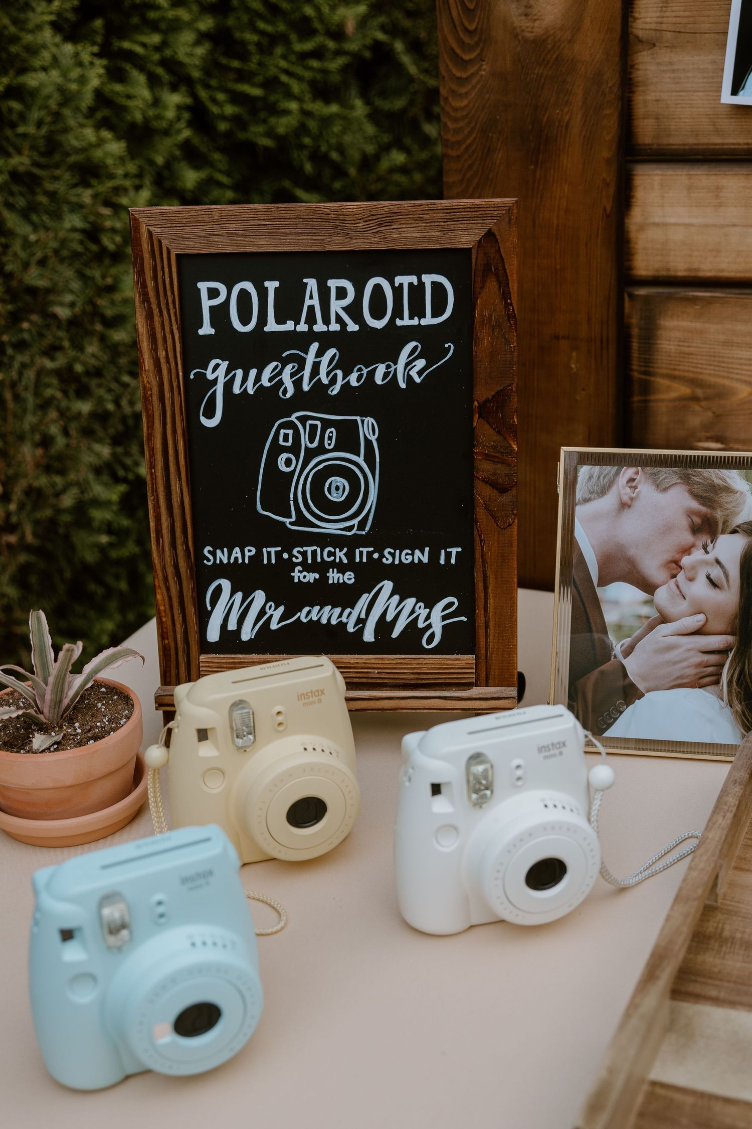 Vintage-style Polaroid cameras and chalkboard signs displayed at a rustic wedding reception setup.