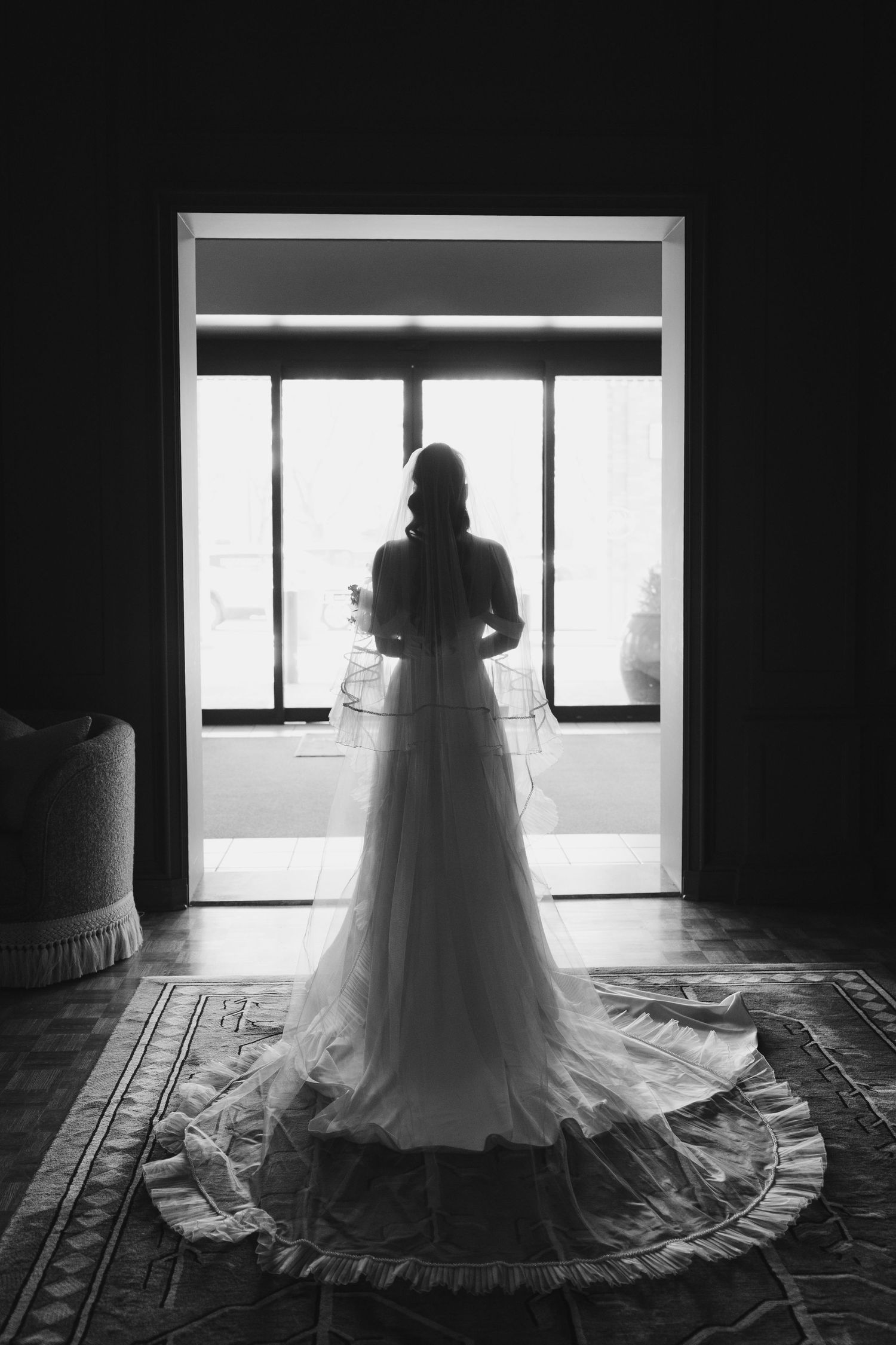 A silhouette of a bride in a flowing wedding gown stands in a dark room located at The Whitman Hotel in Walla Walla, Washington.